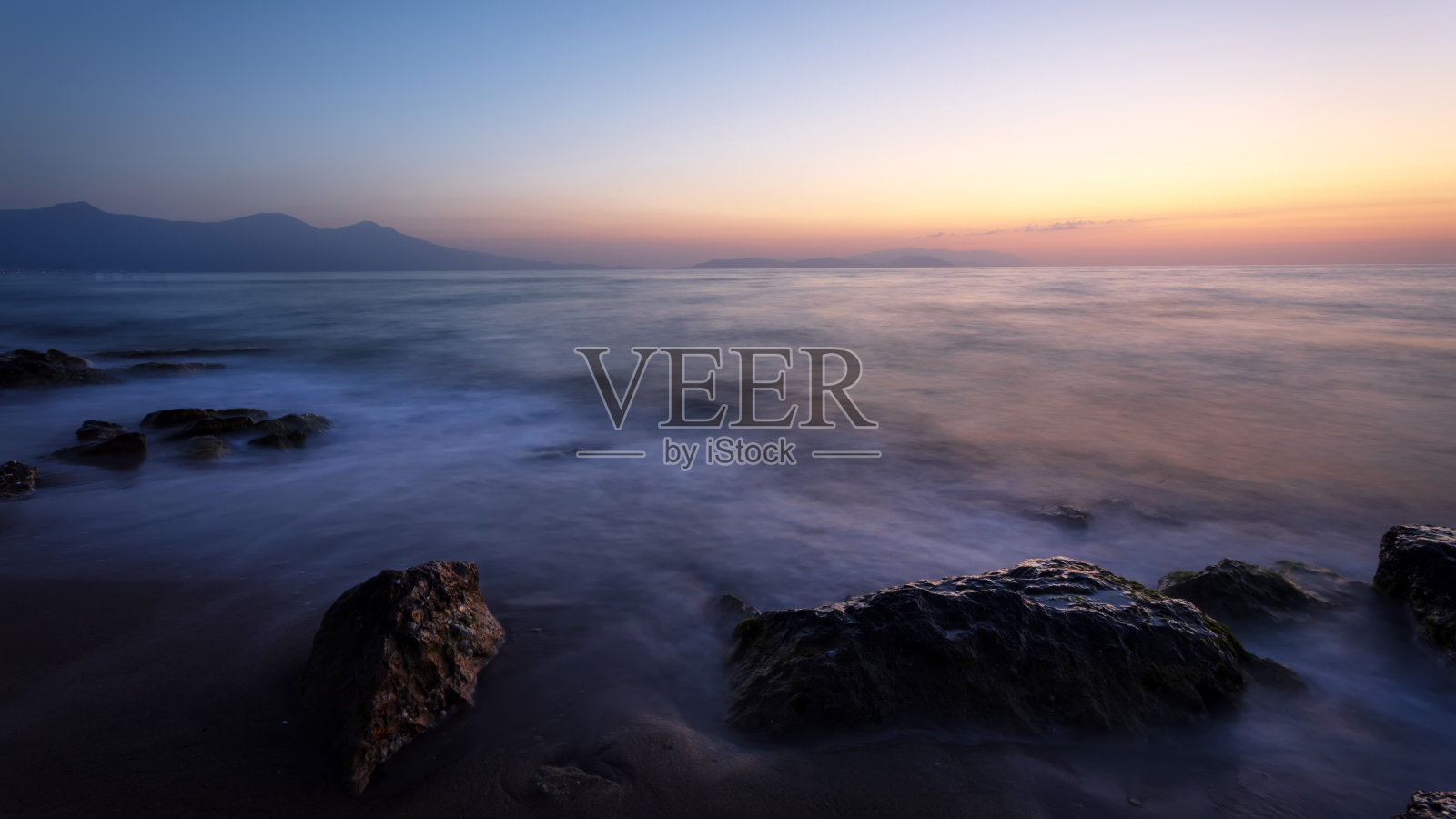 日落时用长曝光技术拍摄的海景。照片摄影图片