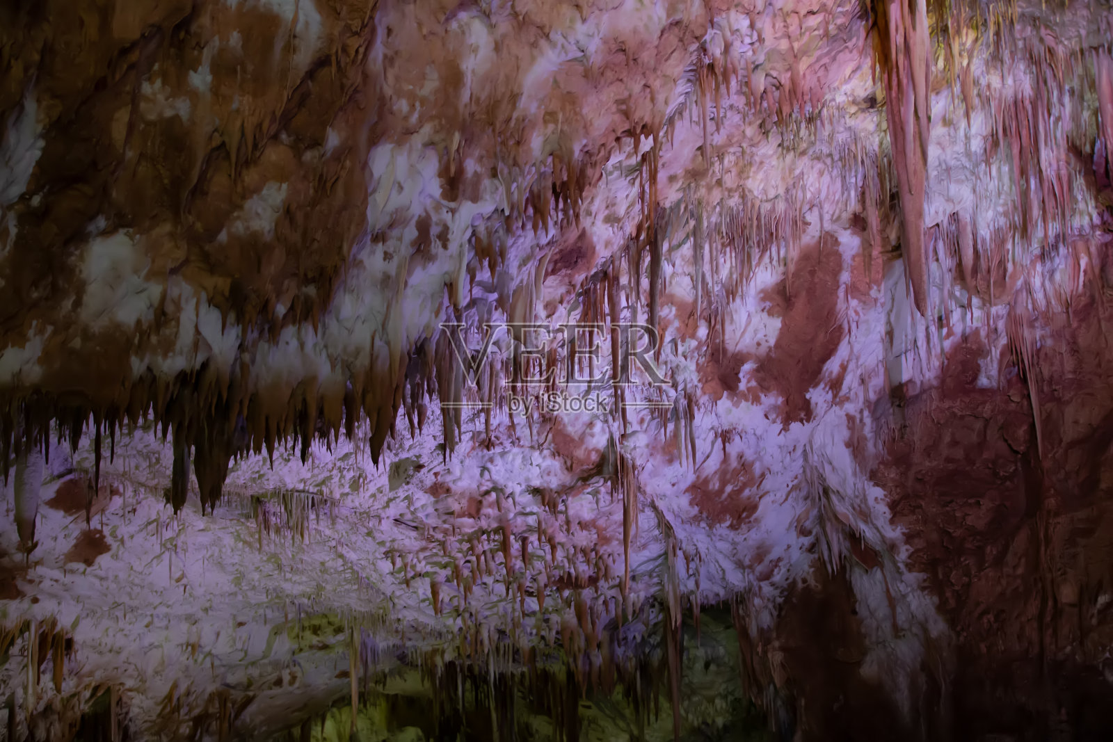 喀斯特溶洞中，钟乳石和钟乳石在五彩斑斓的明亮灯光下令人叹为观止，是美丽的自然旅游地标。照片摄影图片