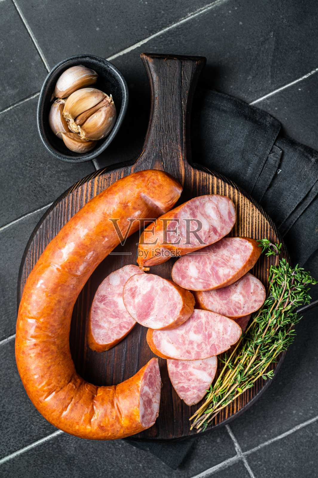 切好的克拉科夫烟熏香肠放在木板上。黑色背景。俯视图照片摄影图片