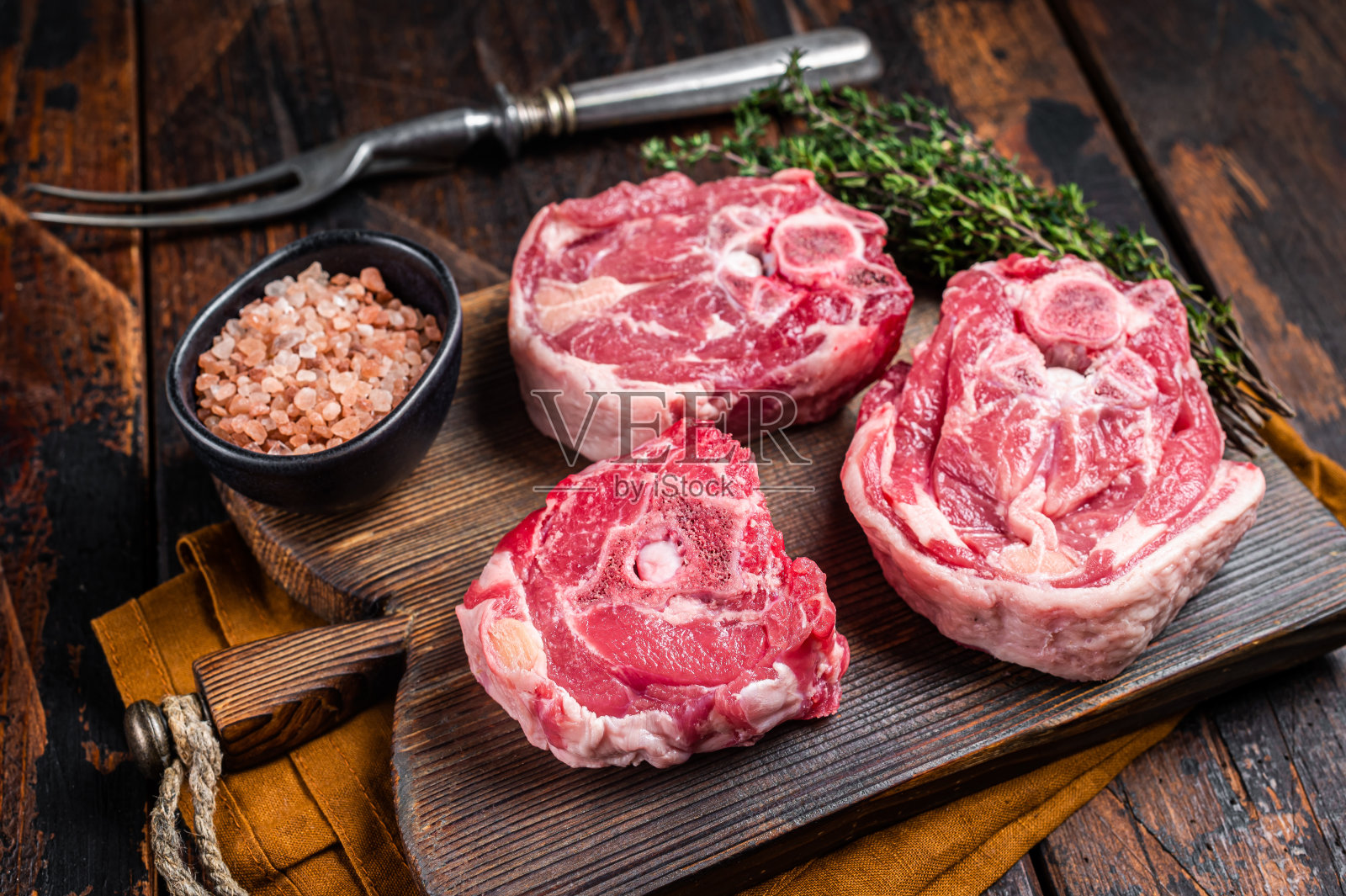 新鲜的生羊颈肉，带骨，用香草放在木板上。木制背景。俯视图照片摄影图片