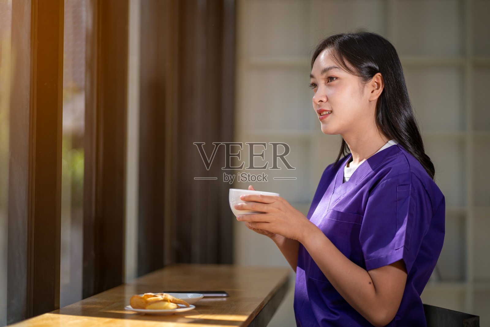 放松的女医生喝咖啡，在休息时间打电话聊天，吃零食。照片摄影图片