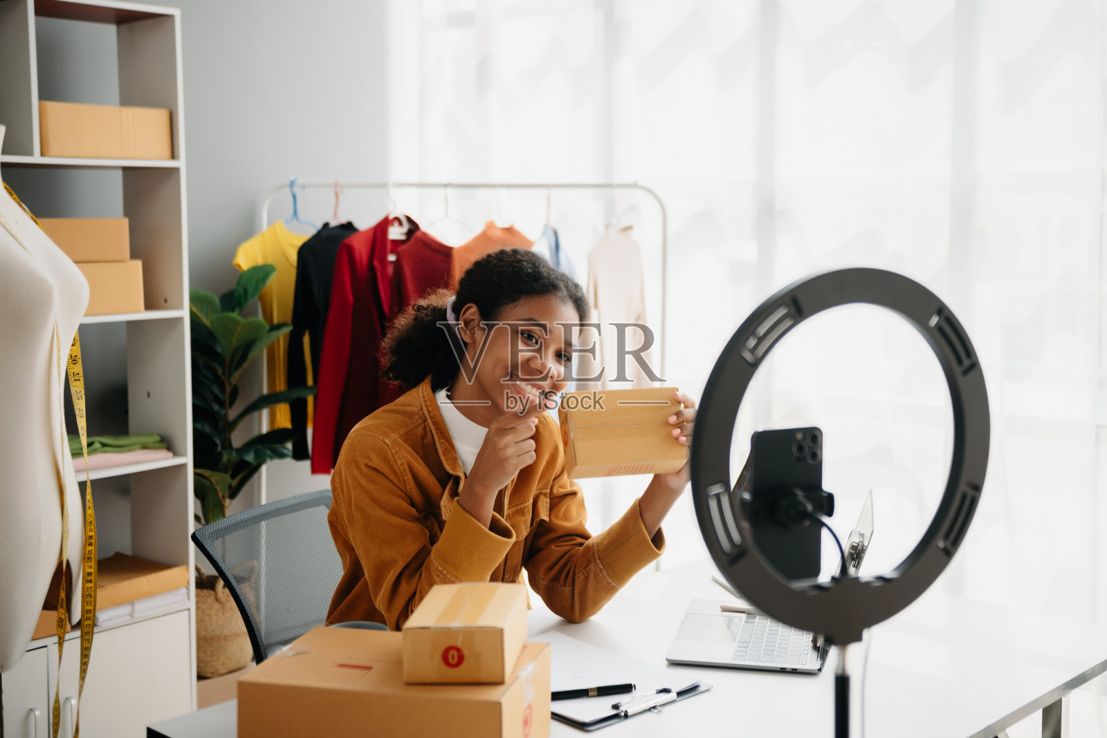 不同的女性时装设计师们脖子上戴着“裁缝厘米”，手里拿着平板电脑和智能手机。独立创意设计业务。照片摄影图片
