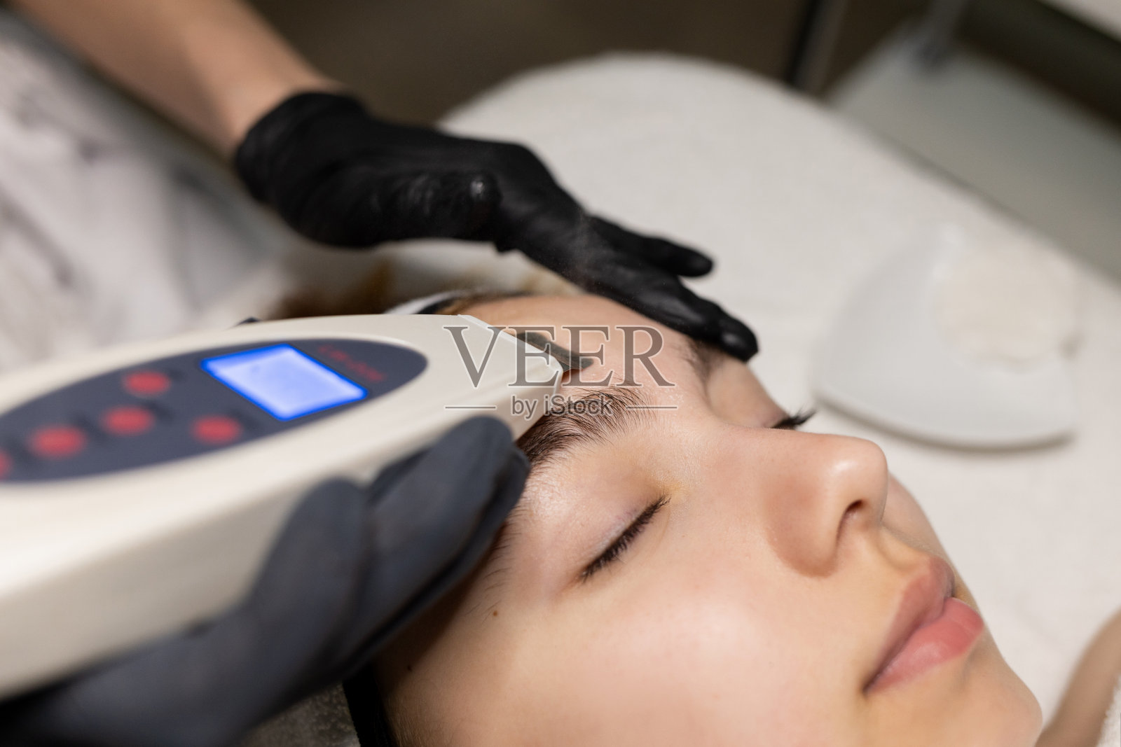 美丽快乐的年轻女子，皮肤完美，闭着眼睛微笑，在美容师办公室做面部护理。照片摄影图片