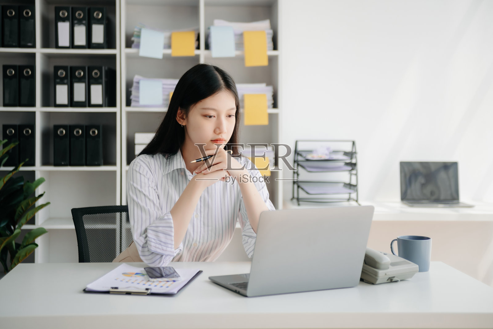 年轻漂亮的女人坐在办公木桌前，在平板电脑和笔记本电脑上打字照片摄影图片