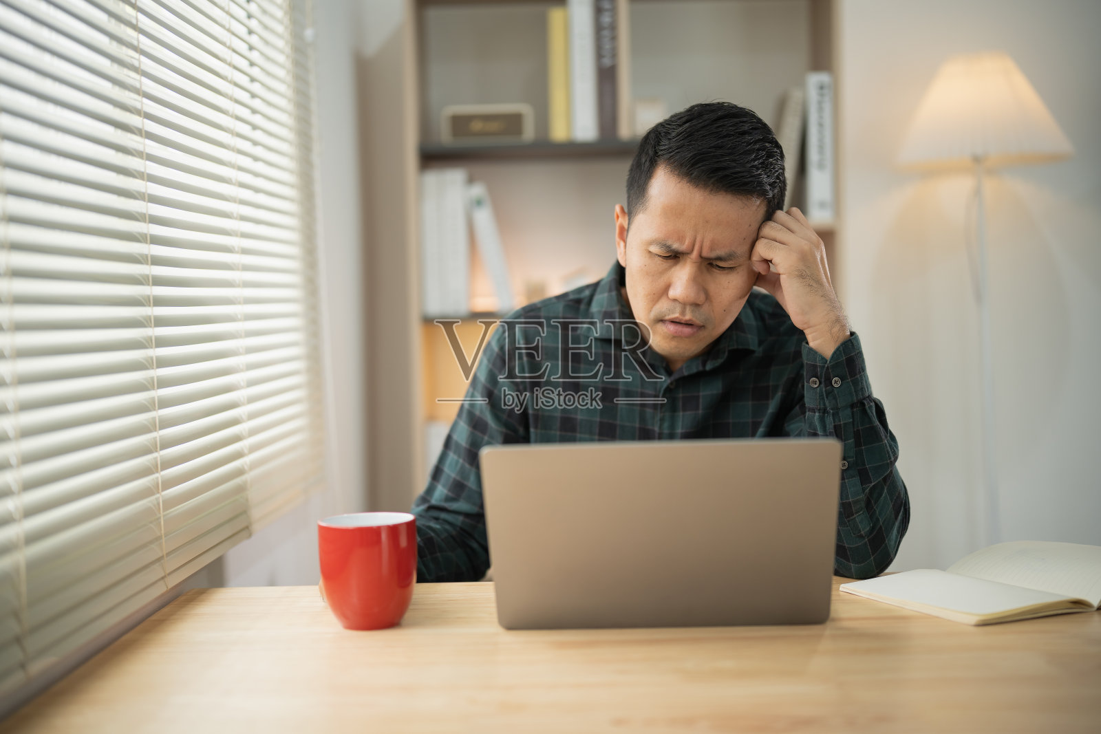 亚洲自由职业者有压力抑郁症悲伤的时间，而工作视频会议在笔记本电脑上。抑郁症男子表示，在家工作严重。在任何地方工作的概念。照片摄影图片