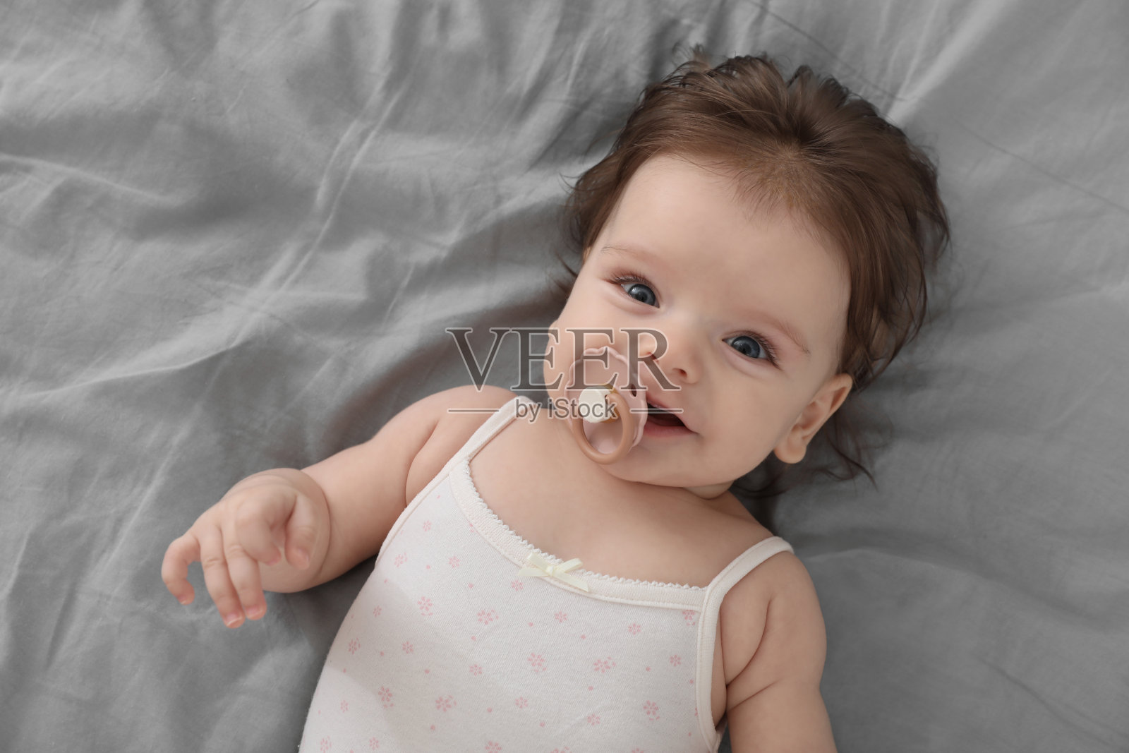 床上可爱的小婴儿带着奶嘴，俯视图照片摄影图片