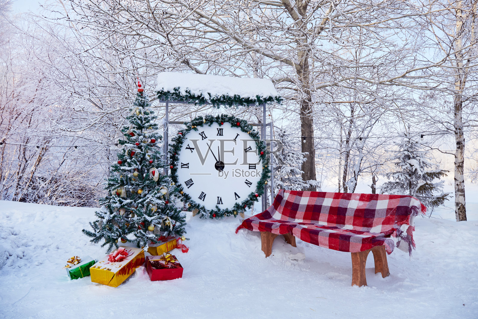 冬天，城市公园里有一棵有玩具的圣诞树，一个巨大的钟。白雪覆盖的树木，霜冻的日子照片摄影图片