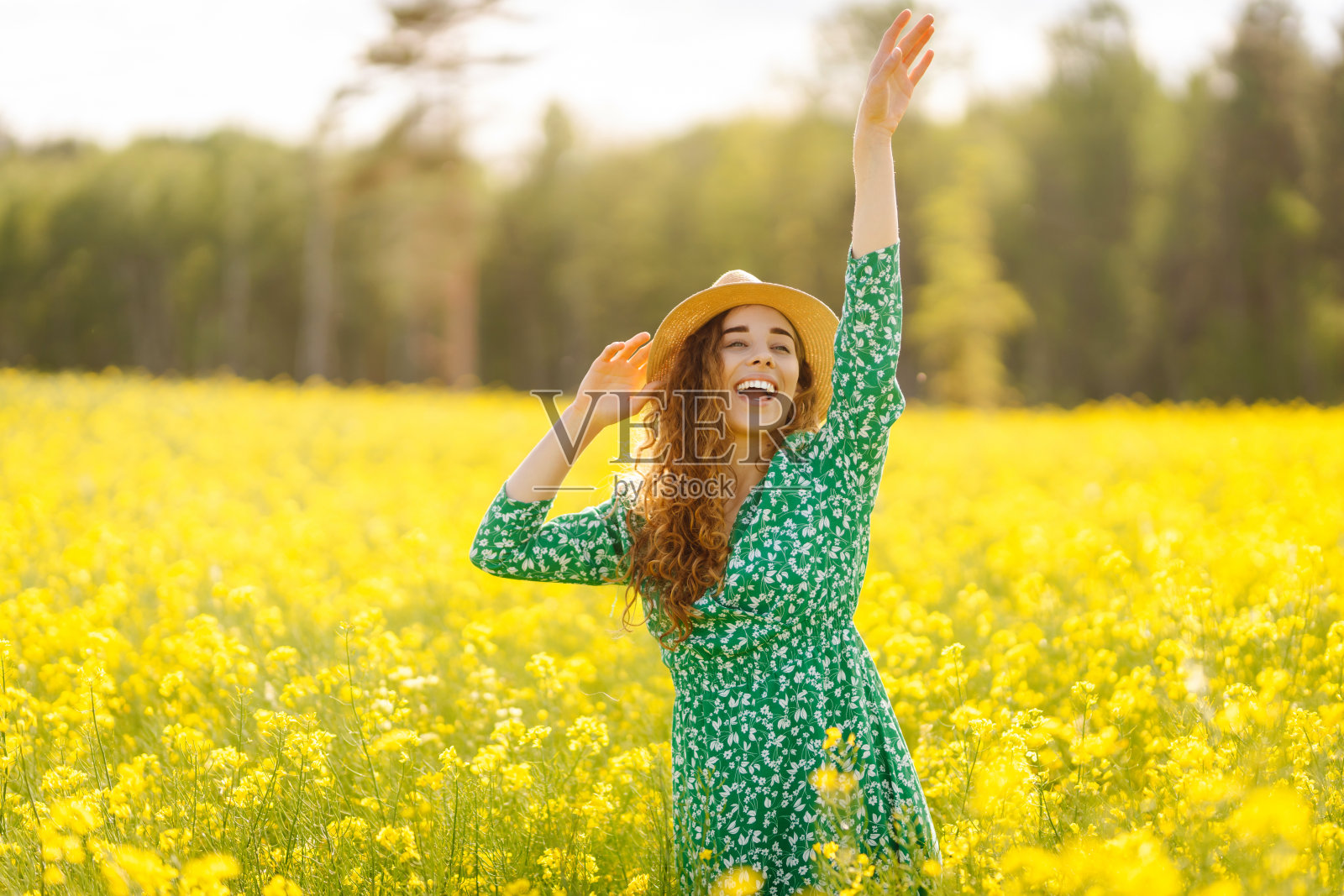 一位年轻女子走过一片盛开的田野，轻轻地抚摸着黄色的花朵。照片摄影图片