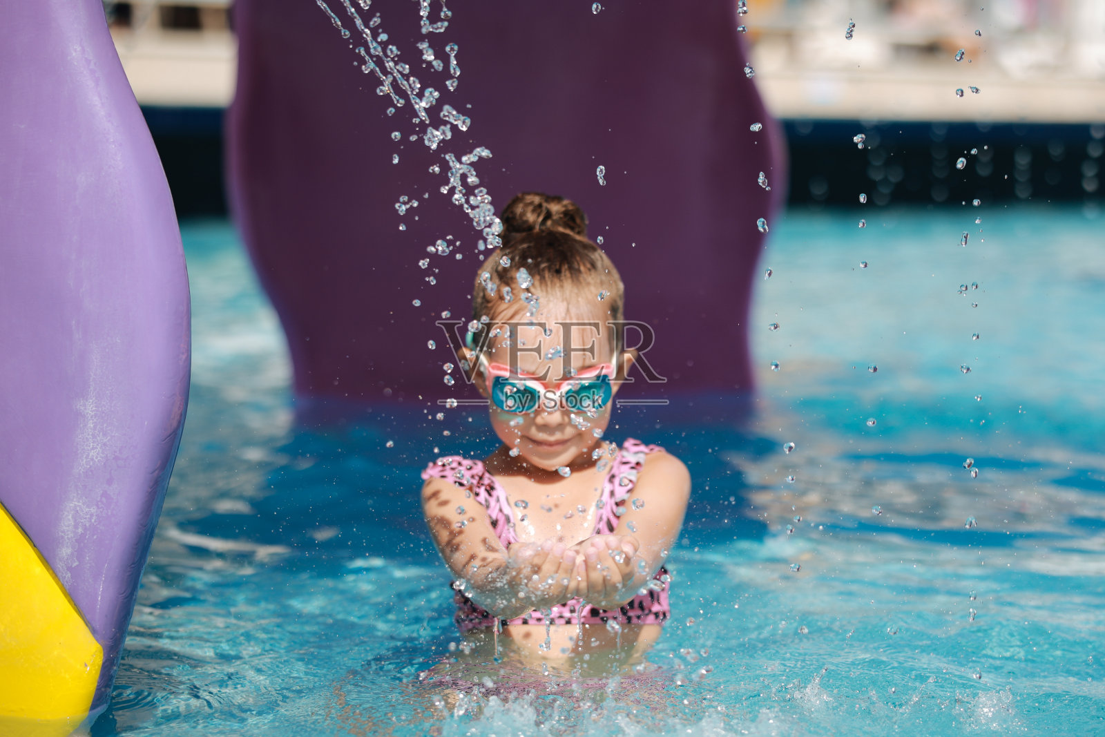 快乐的笑着蹒跚学步的女孩在游泳池里玩耍照片摄影图片