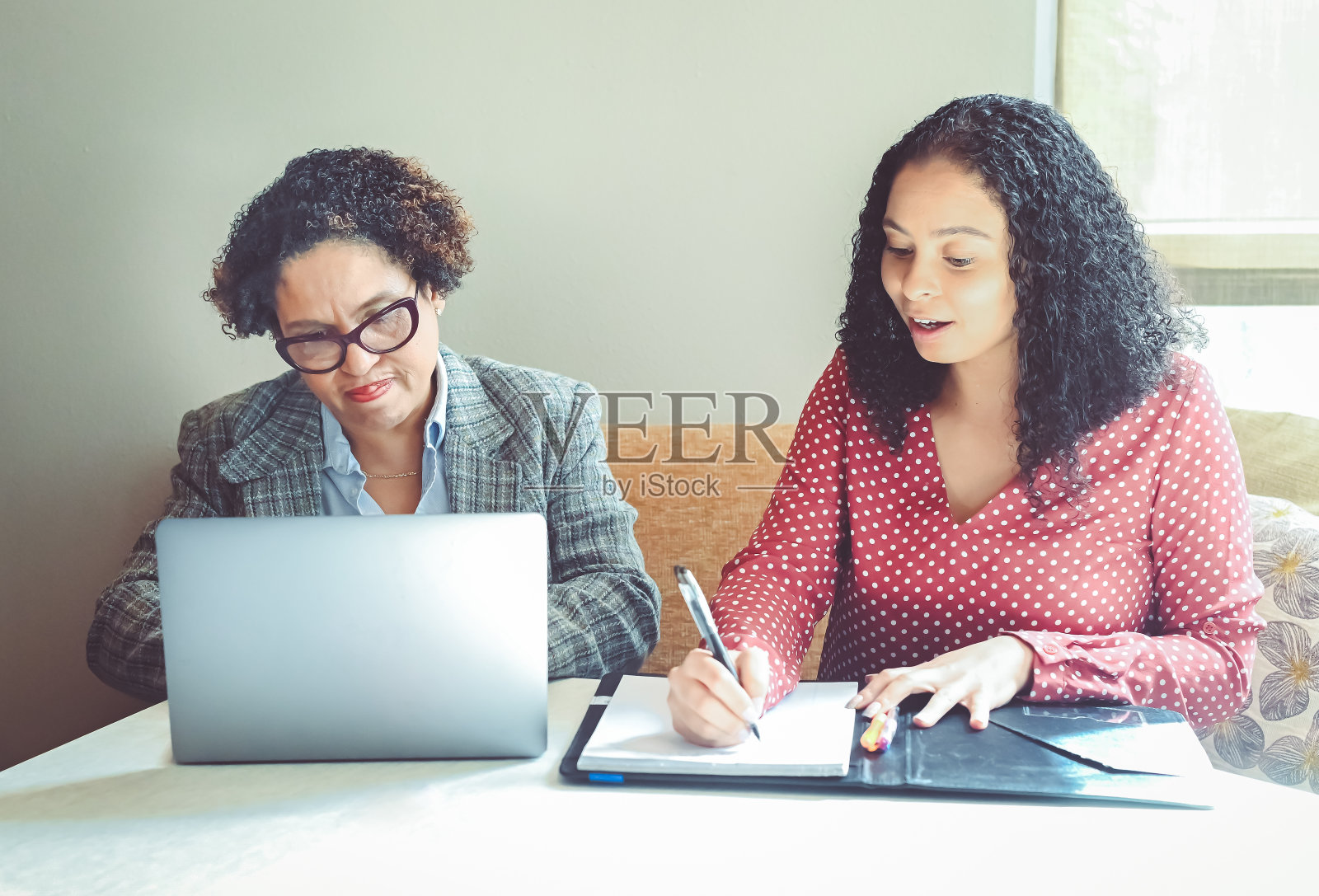 两个多种族的职业女性，同事，合作伙伴，或者客户和代理人，带着笔记本电脑照片摄影图片