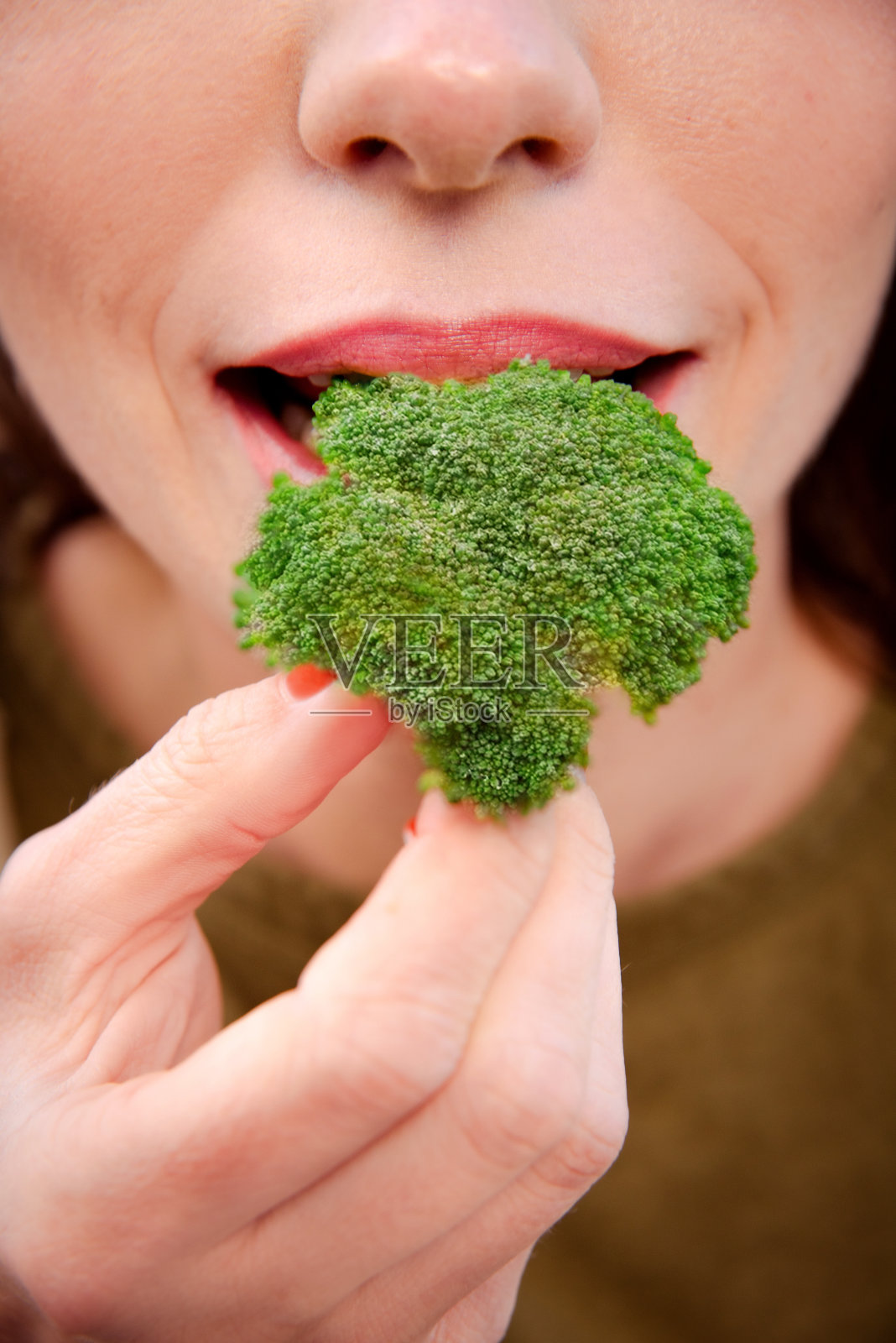 西兰花的好处。女人品尝健康的绿西兰花。垂直图照片摄影图片