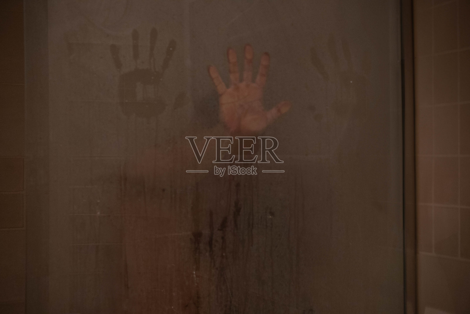 一个40岁的男人在淋浴，一只手倚在满是蒸汽的喷头上。照片摄影图片