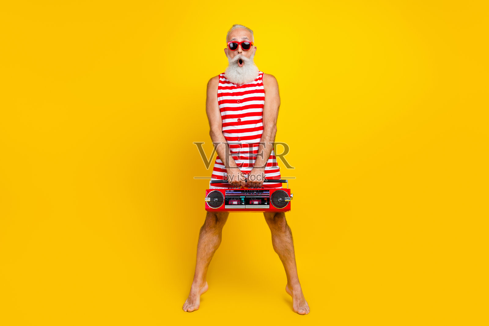 疯狂的游客的全身照片惊讶的退休老人保持踮起脚尖拿着时髦的立体声音箱孤立的黄色背景照片摄影图片