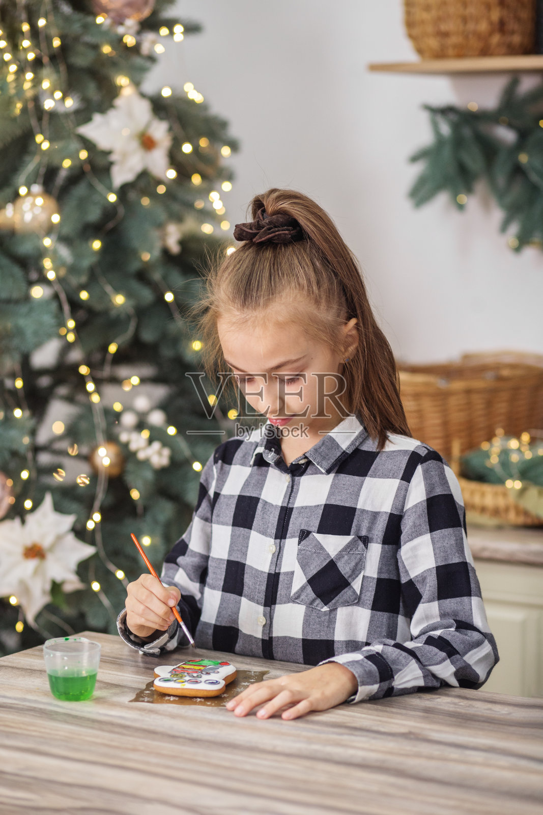 小女孩在圣诞节自制的姜饼饼干上画食物颜料。圣诞节的概念照片摄影图片