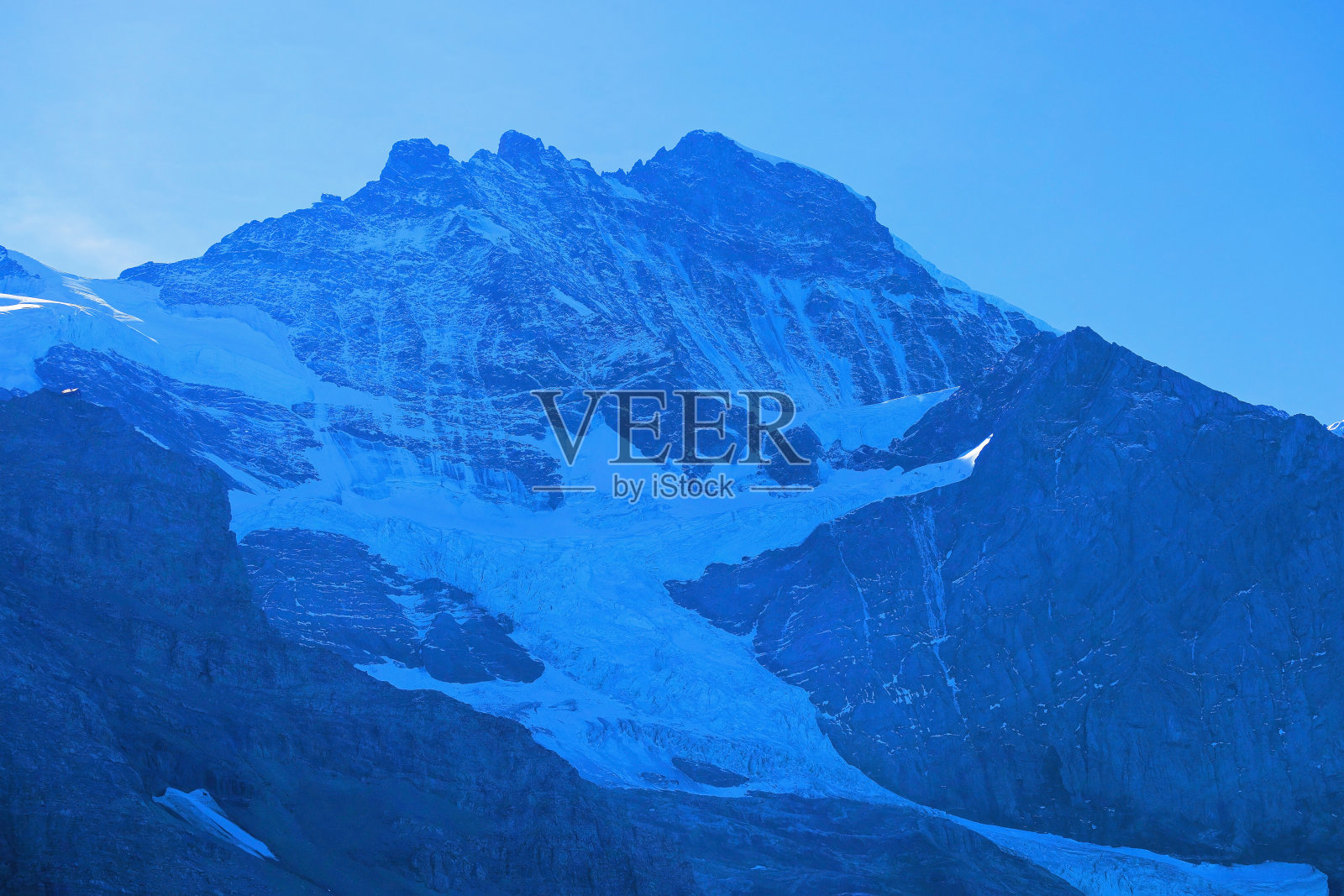 湛蓝的天空下，蓝灰色的山脉和冰川，瑞士少女峰照片摄影图片