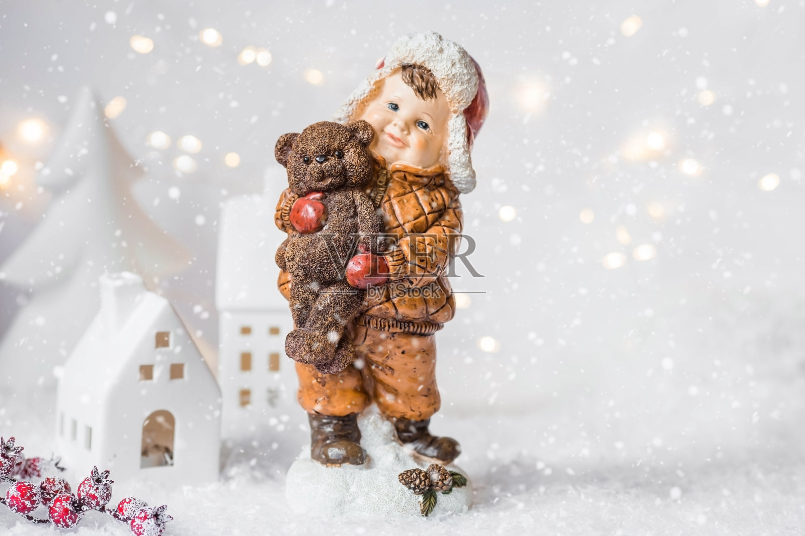 在美丽的白雪覆盖的背景上，有一个可爱的孩子形象的复古圣诞贺卡。一个戴着帽子的男孩抱着一只熊宝宝。2024年元旦寒假概念。照片摄影图片