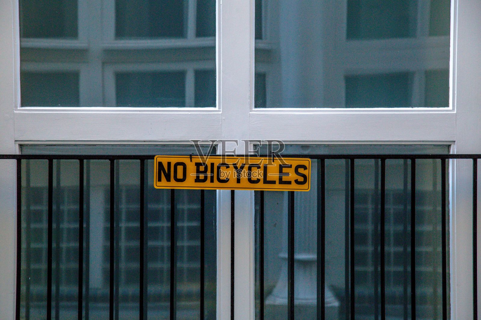 大楼前的金属栅栏上有黄色的“禁止自行车”标志照片摄影图片