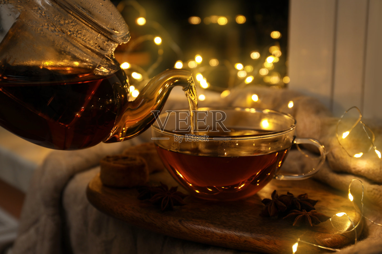 在室内将香茴香茶倒入木板上的玻璃杯中，产生散景效果照片摄影图片