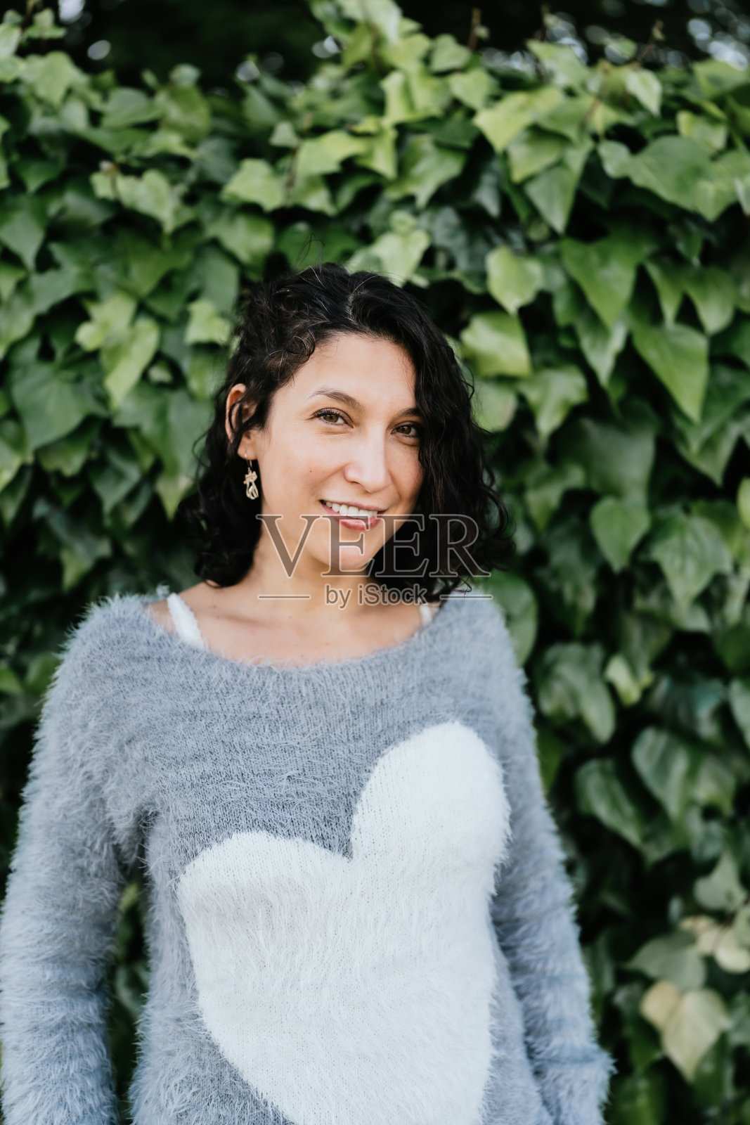 站在绿叶背景前的拉丁妇女肖像照片摄影图片