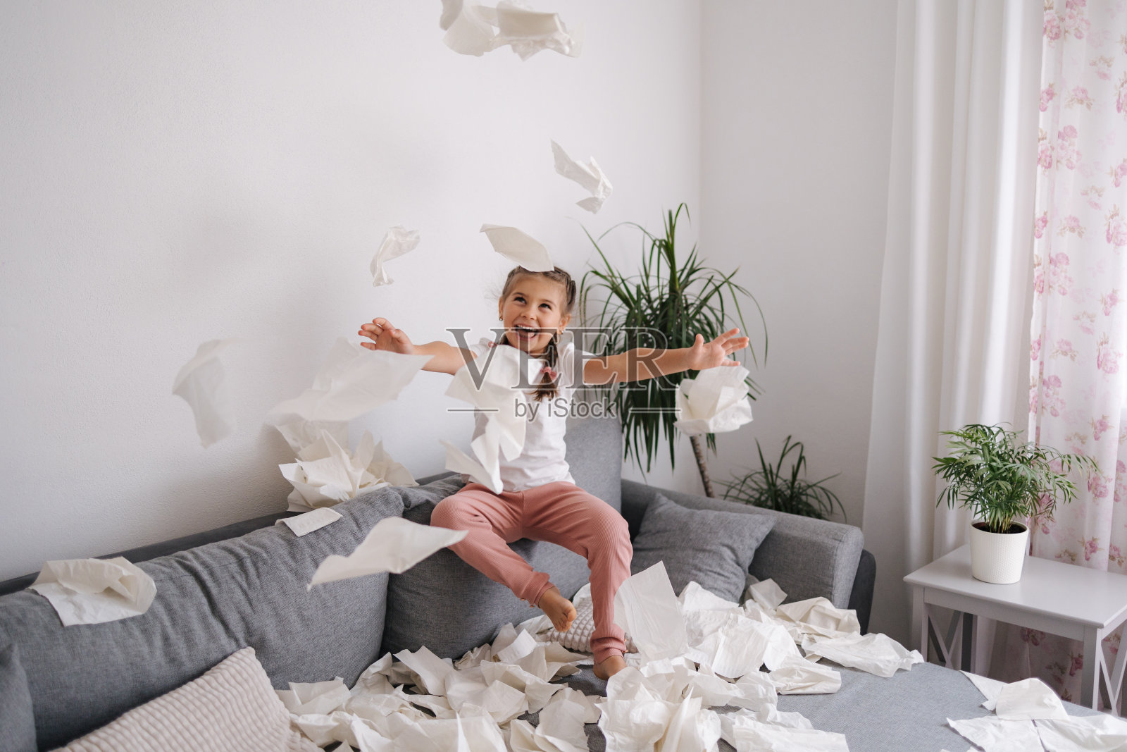 可爱的小女孩把家里弄得一团糟。五岁的小女孩把餐巾纸扔进了客厅照片摄影图片