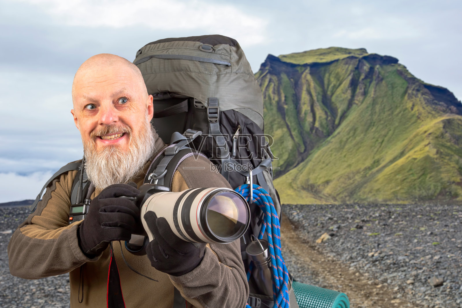 一名大胡子的旅游摄影师背着背包，在山上拍摄大自然之美。大自然在山间漫步照片摄影图片