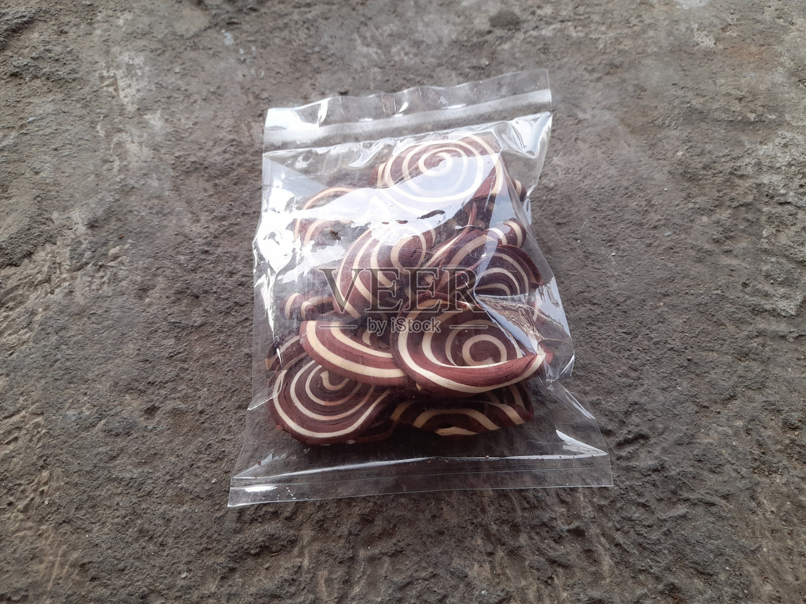 印尼传统食品象耳饼，用塑料做成，背景是街道纹理照片摄影图片