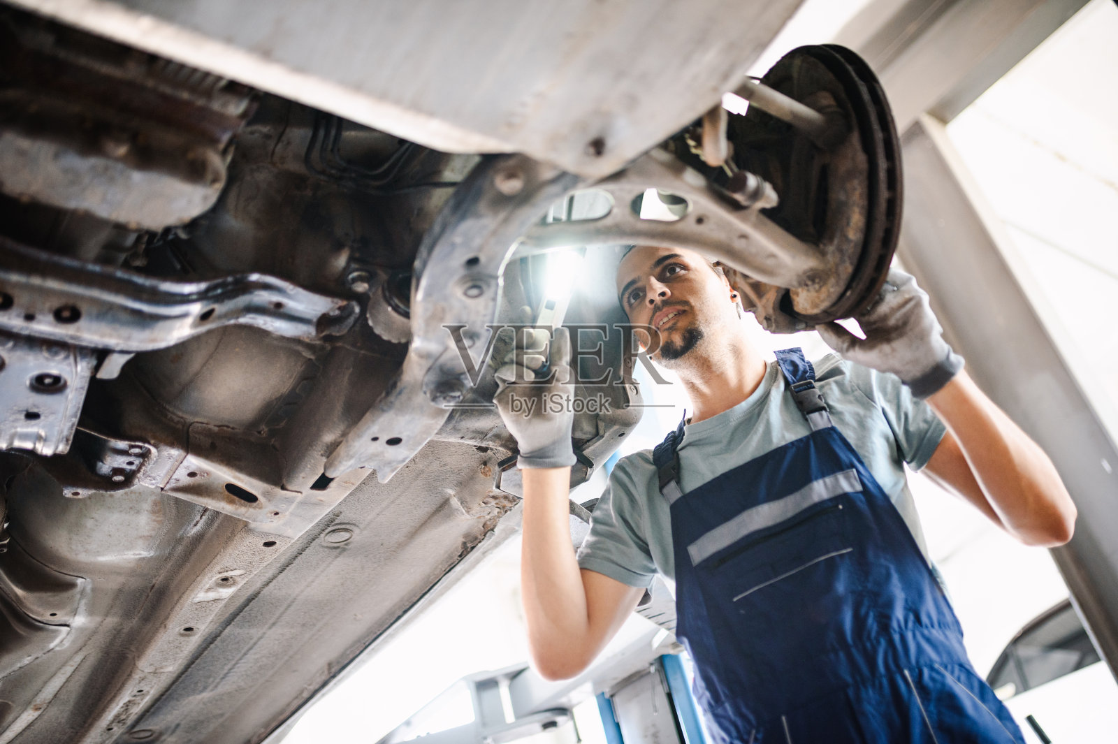 汽车修理工检查汽车悬架。诊断汽车的状况照片摄影图片