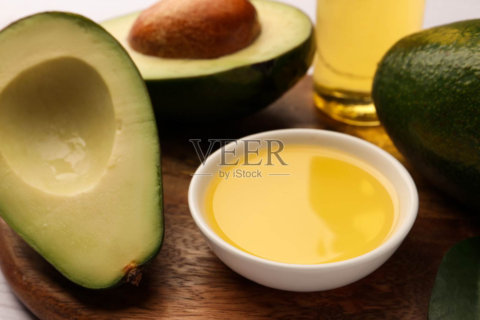 碗里盛着食用油，木桌上放着新鲜的牛油果，特写照片摄影图片