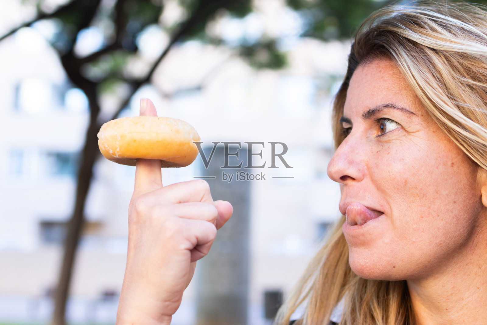 贪心的女人把手指伸进甜甜圈的洞里照片摄影图片