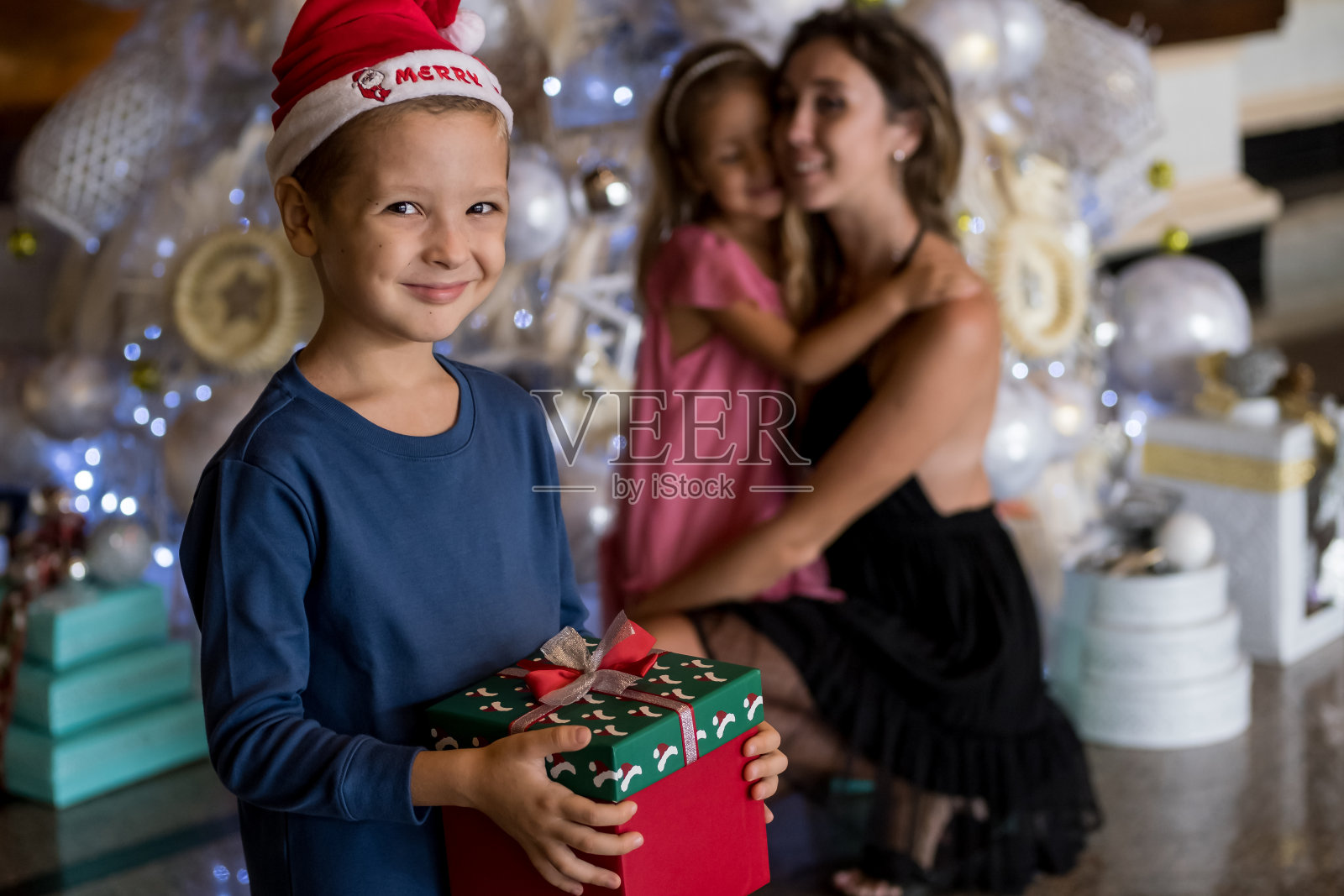 幸福可爱的家庭:妈妈、儿子和女儿在圣诞树旁交换礼物。圣诞快乐，节日快乐照片摄影图片