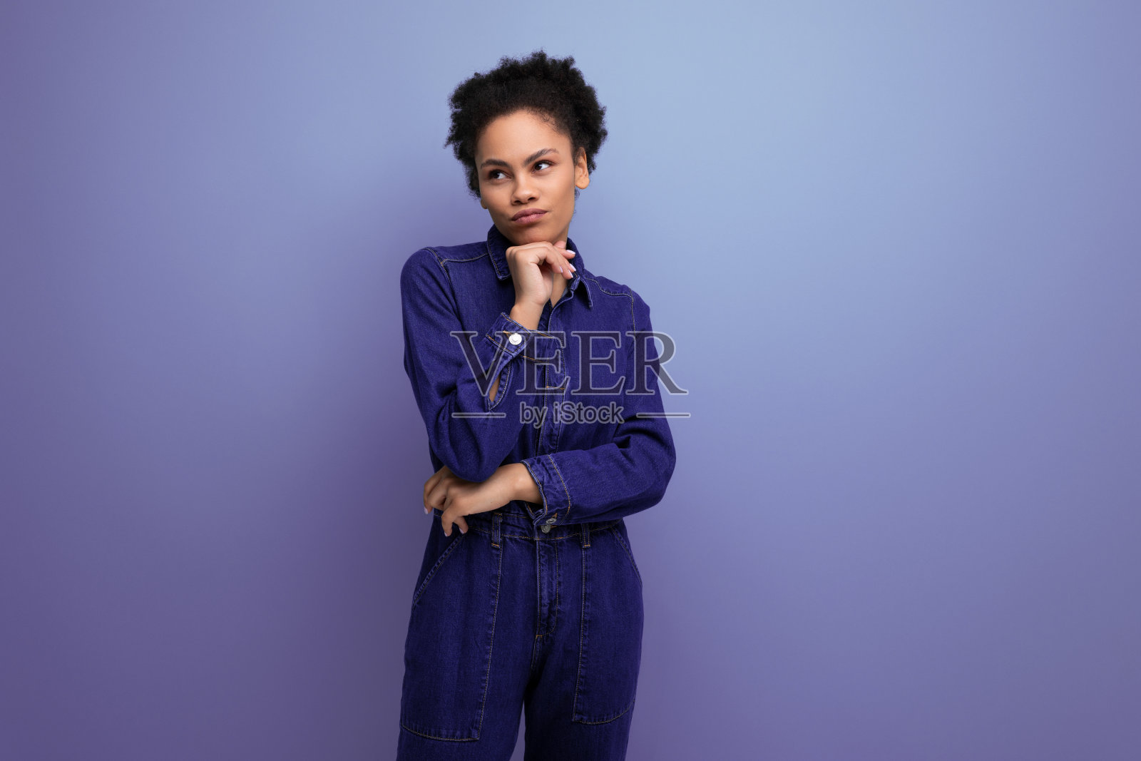 迷人苗条的年轻西班牙裔黑发女人的肖像，蓬松的卷发穿着蓝色牛仔西装照片摄影图片