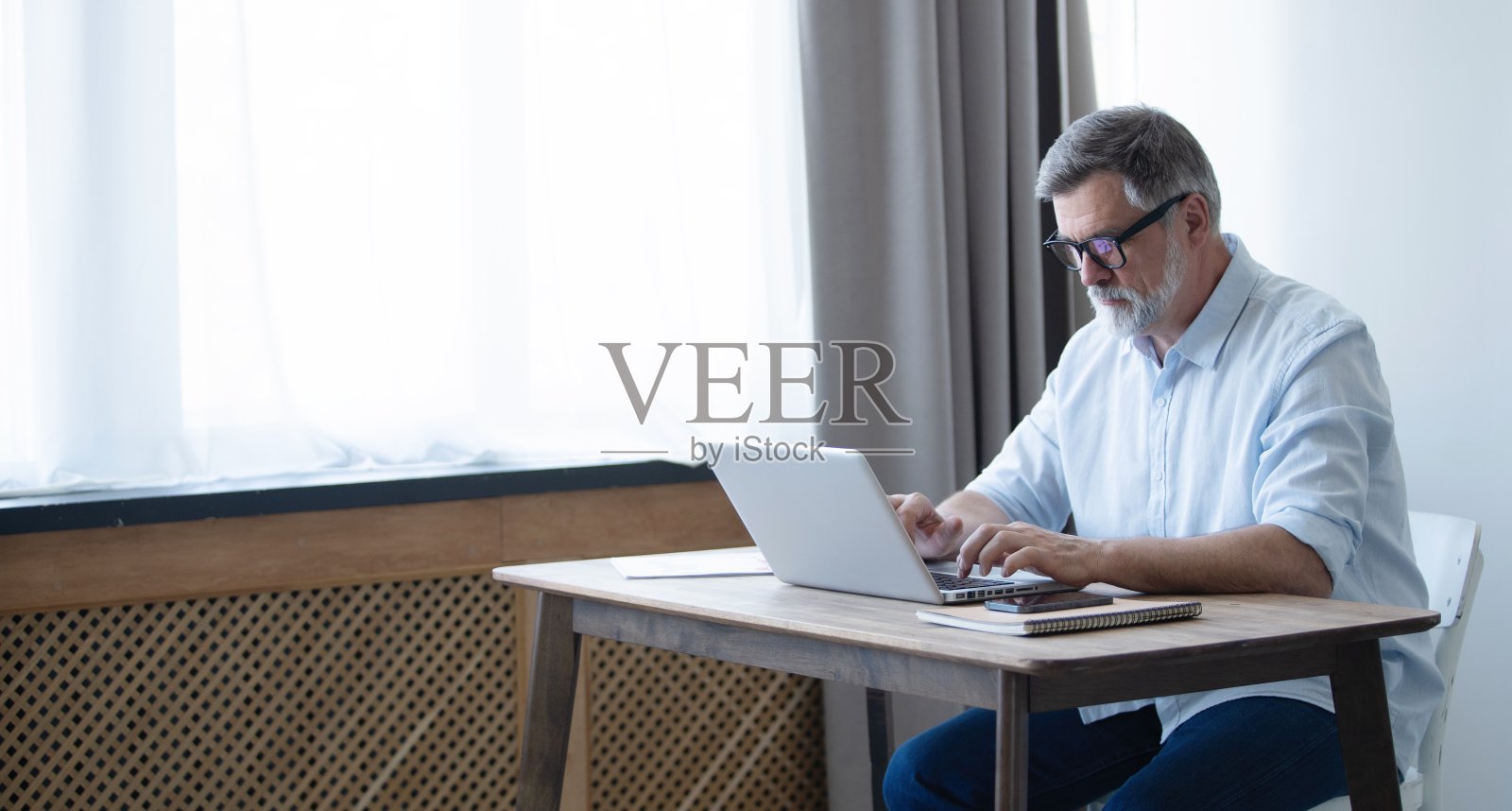 成熟的商人在家里用笔记本电脑工作照片摄影图片