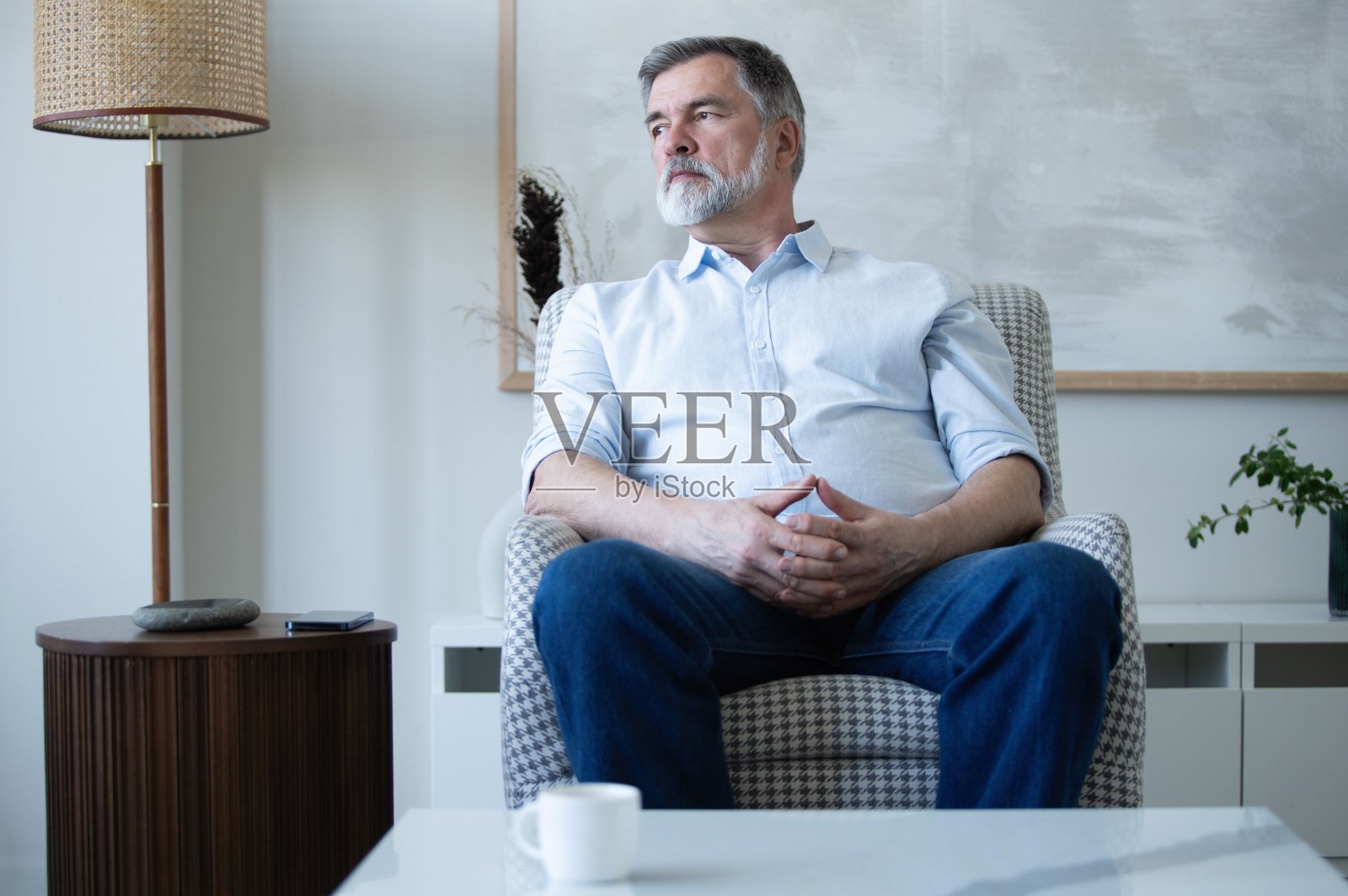 一个快乐的成熟男人坐在家里的沙发上。照片摄影图片