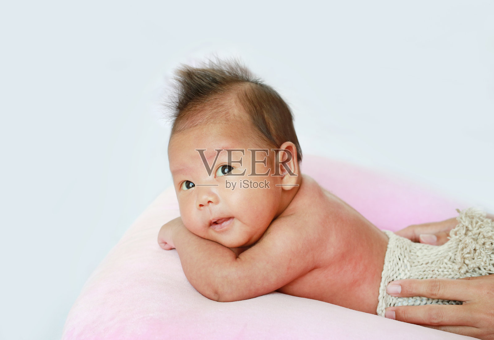 白色背景的婴儿肖像躺在粉红色的枕头上照片摄影图片