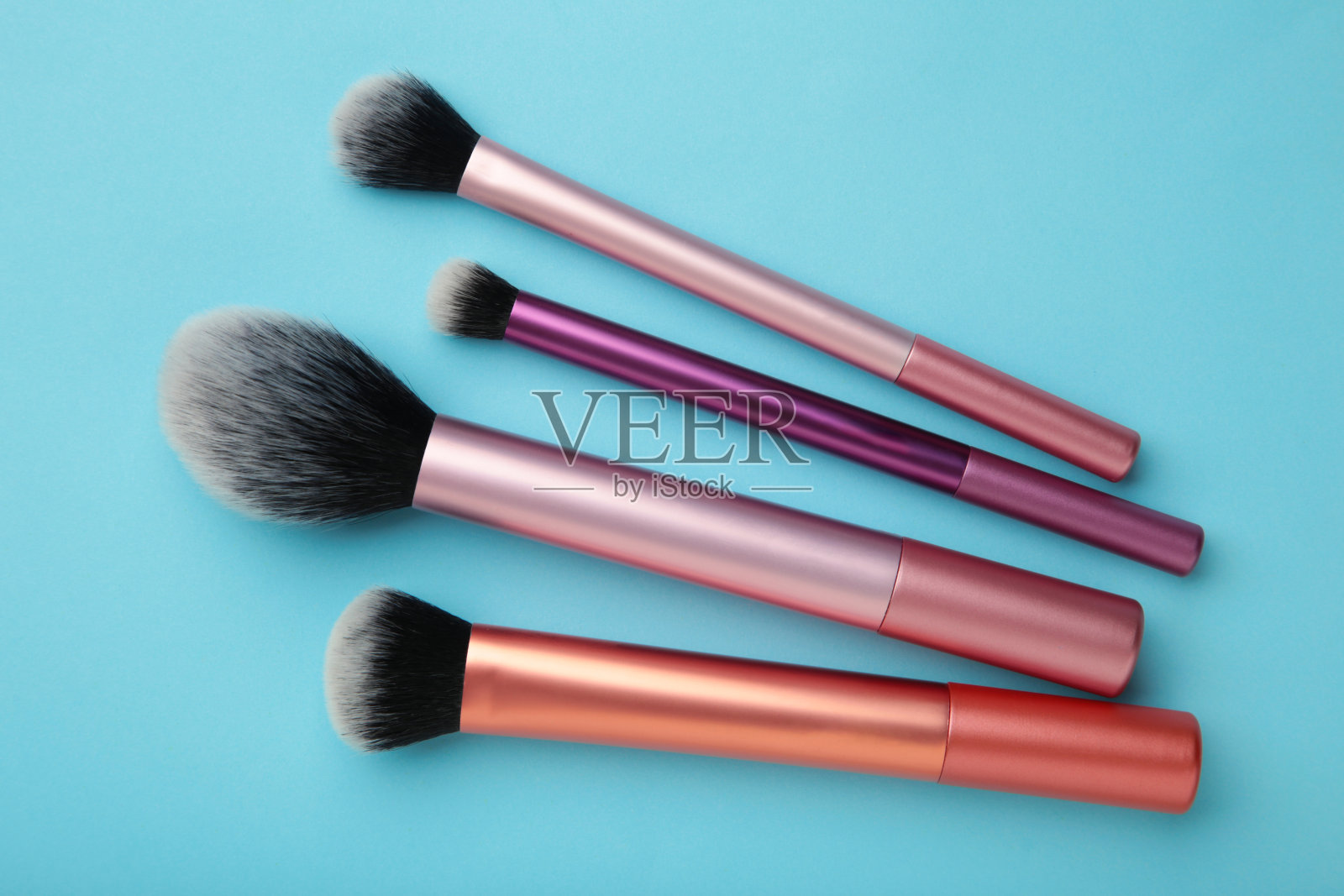 化妆刷组安排在蓝色背景上。化妆品产品。照片摄影图片