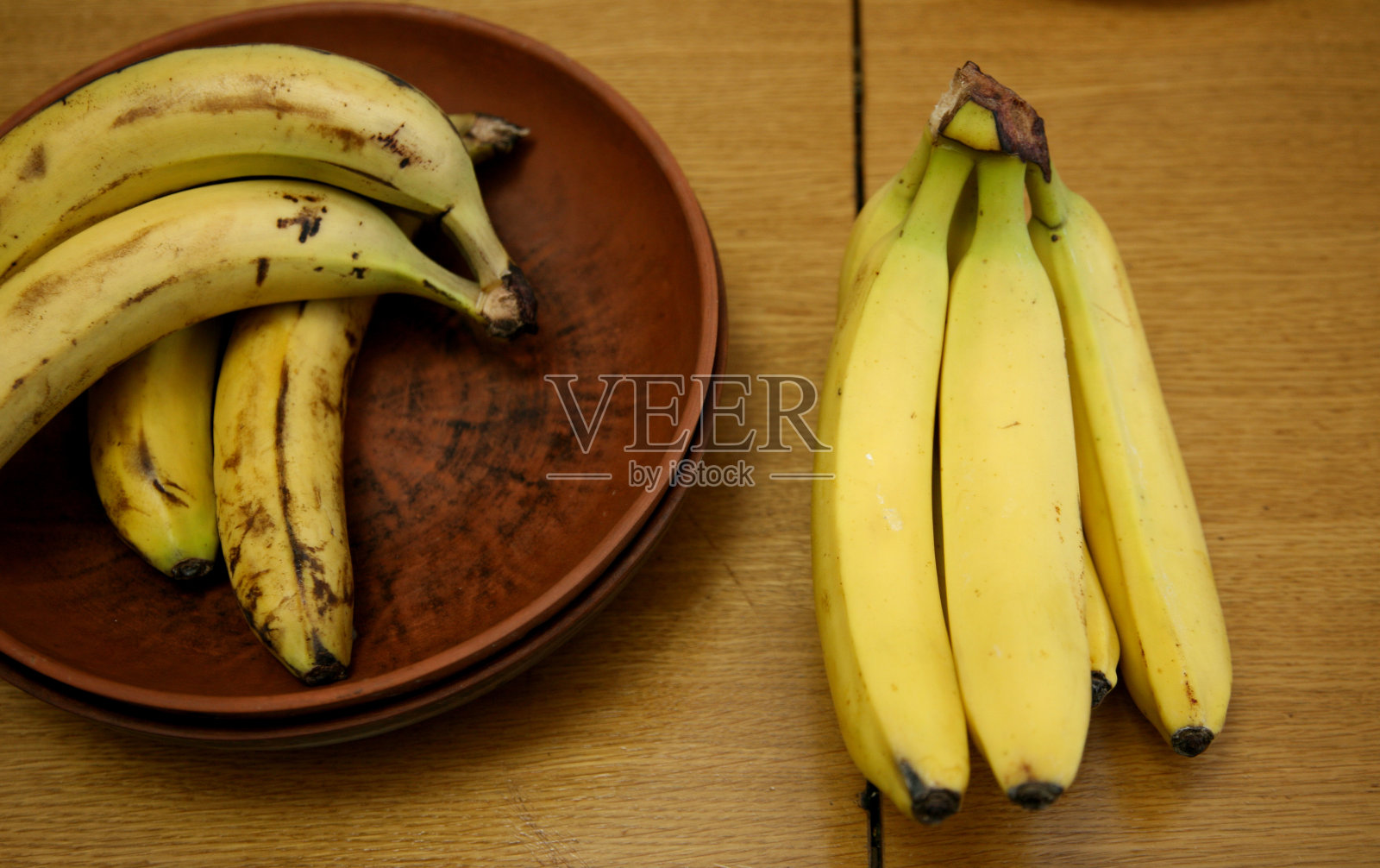 一串香蕉躺在结实的厨房桌子上。甜熟的香蕉，黄皮。厨房里的香蕉和混合水果照片摄影图片