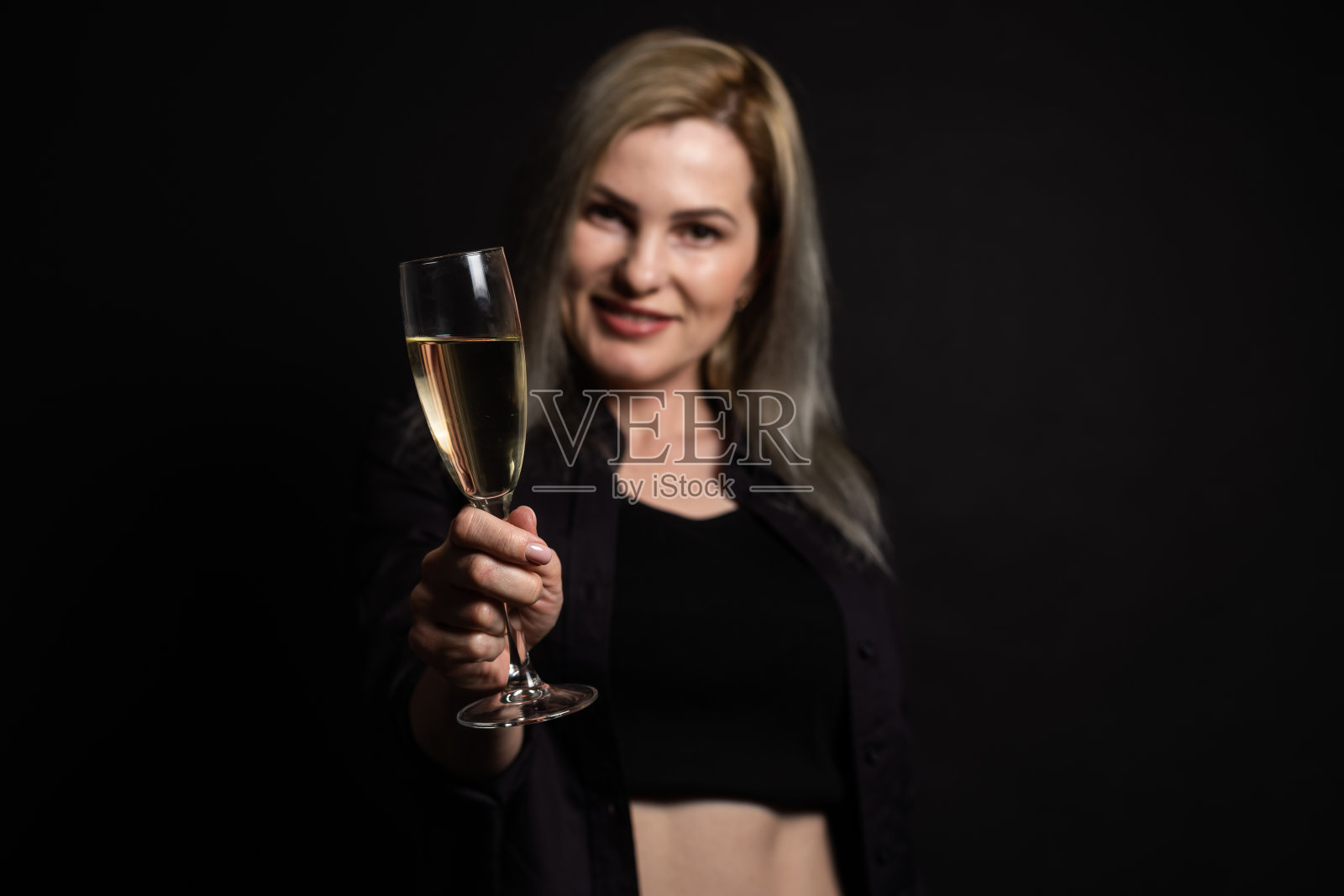 这位性感严厉的女人化着妆，梳着时髦的发型，在黑色背景的工作室里摆姿势。照片摄影图片