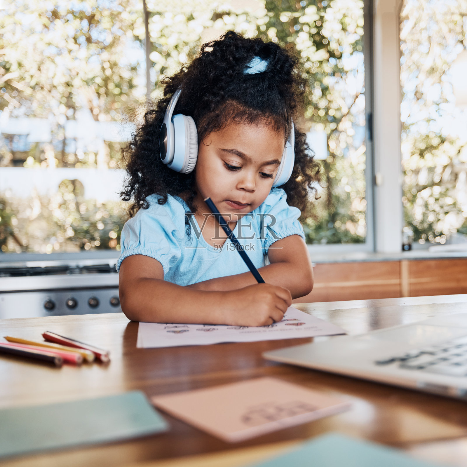 电子学习，笔记本电脑和孩子戴着耳机在书桌上写英语课，为学生的发展和创造性教育。知识，学习和孩子用纸在家里学习和阅读照片摄影图片