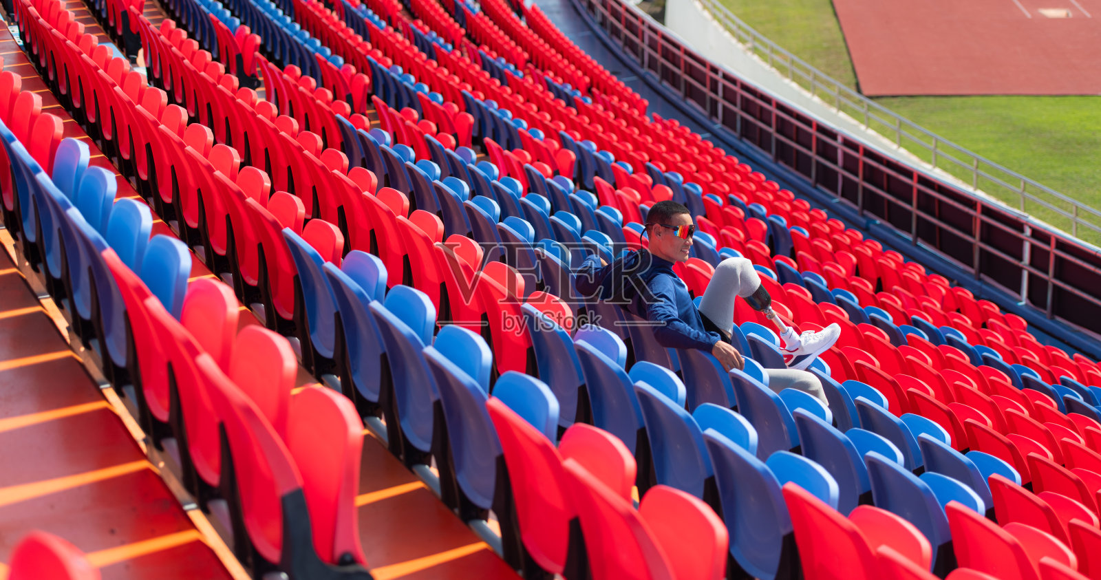 在一个阳光明媚的日子里，残疾人运动员在参加短跑比赛前，在运动场的圆形舞台上准备身体照片摄影图片
