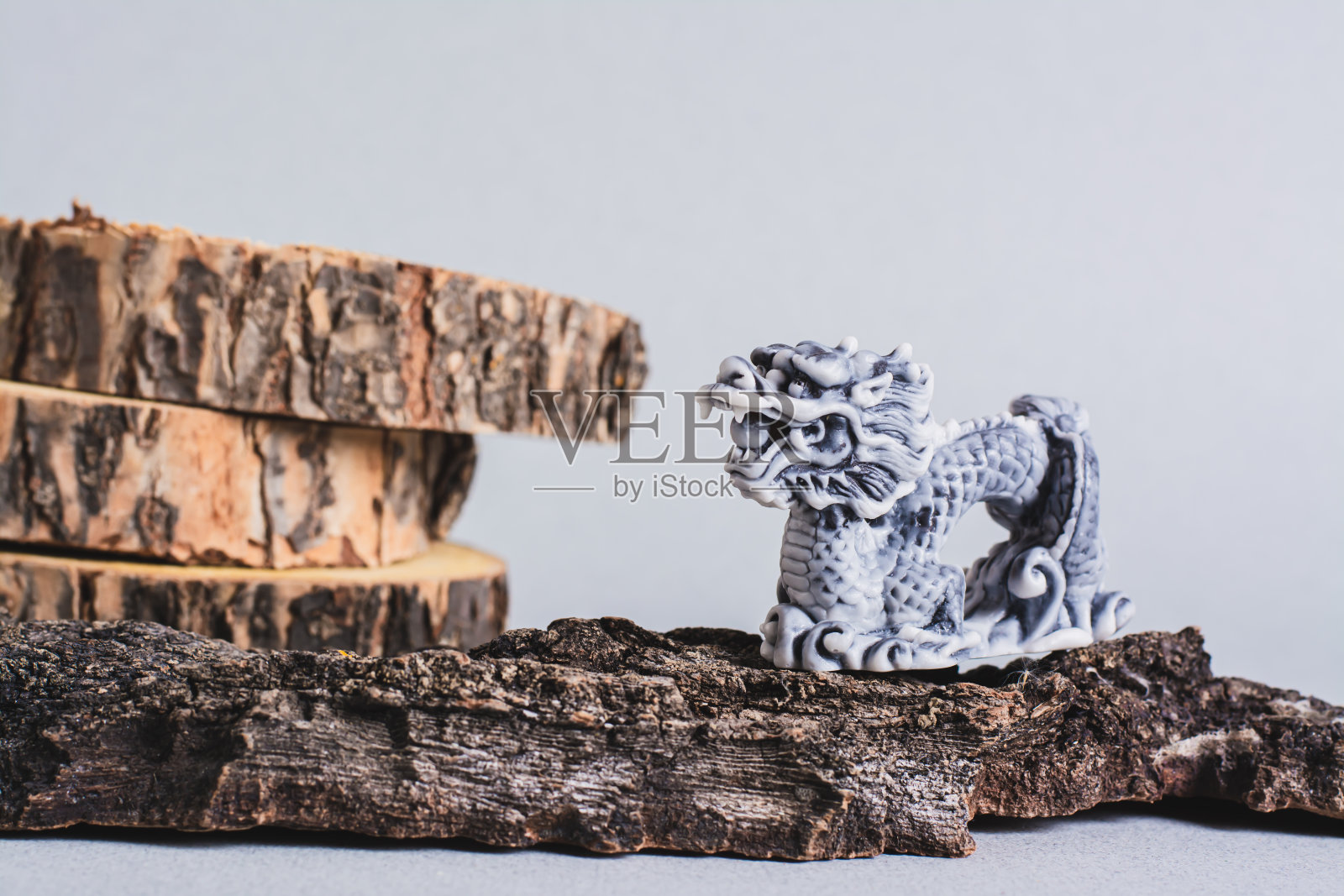灰色背景的树皮和树干上的陶瓷龙照片摄影图片