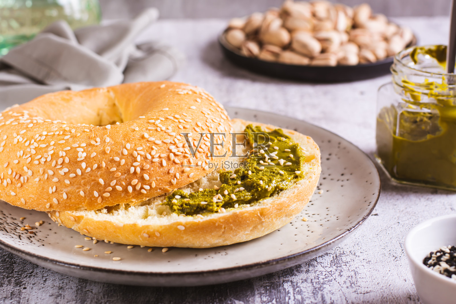 早餐的百吉饼配开心果奶油黄油放在桌上的盘子里照片摄影图片