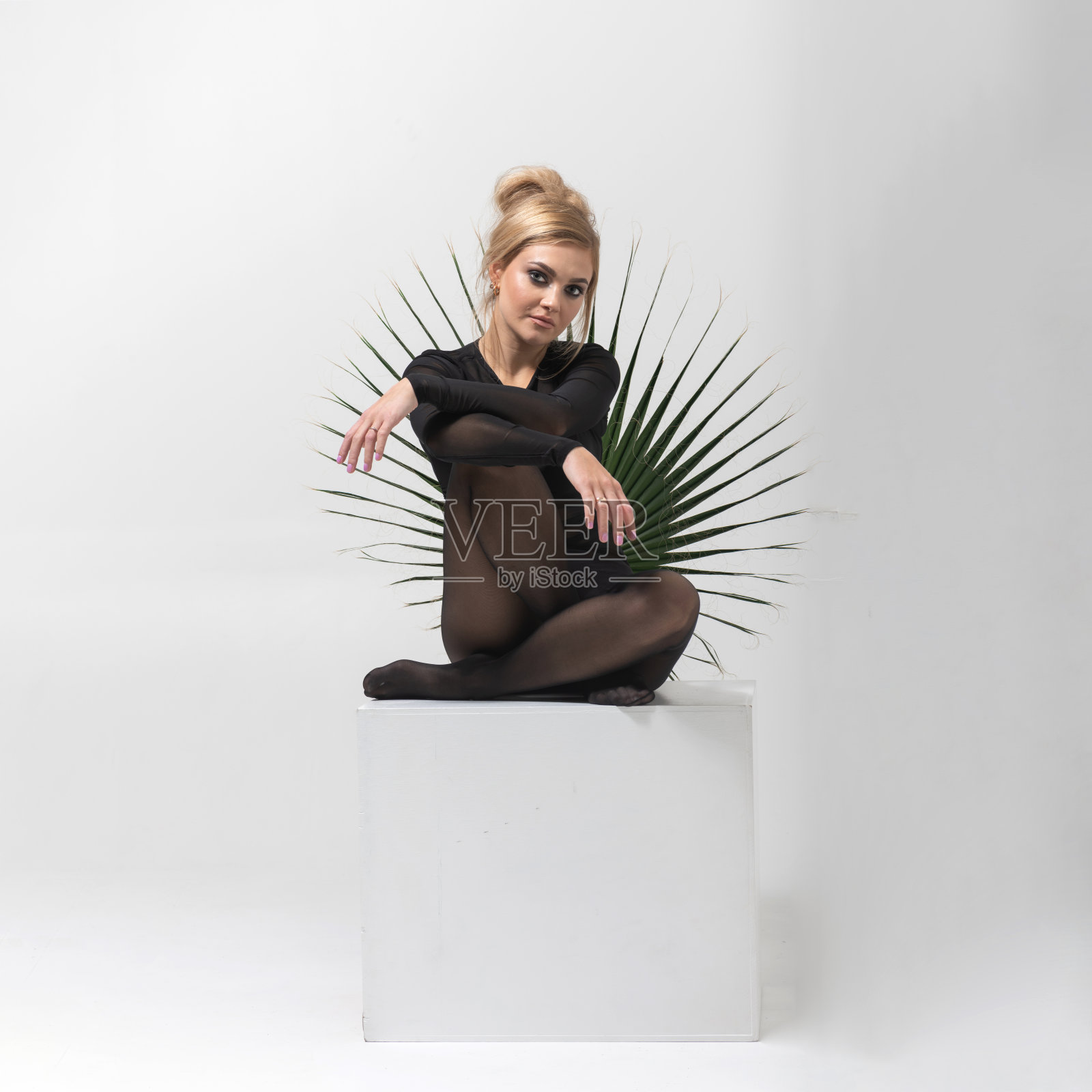 穿着紧身黑衣服的美女肖像坐在白色的立方体上照片摄影图片