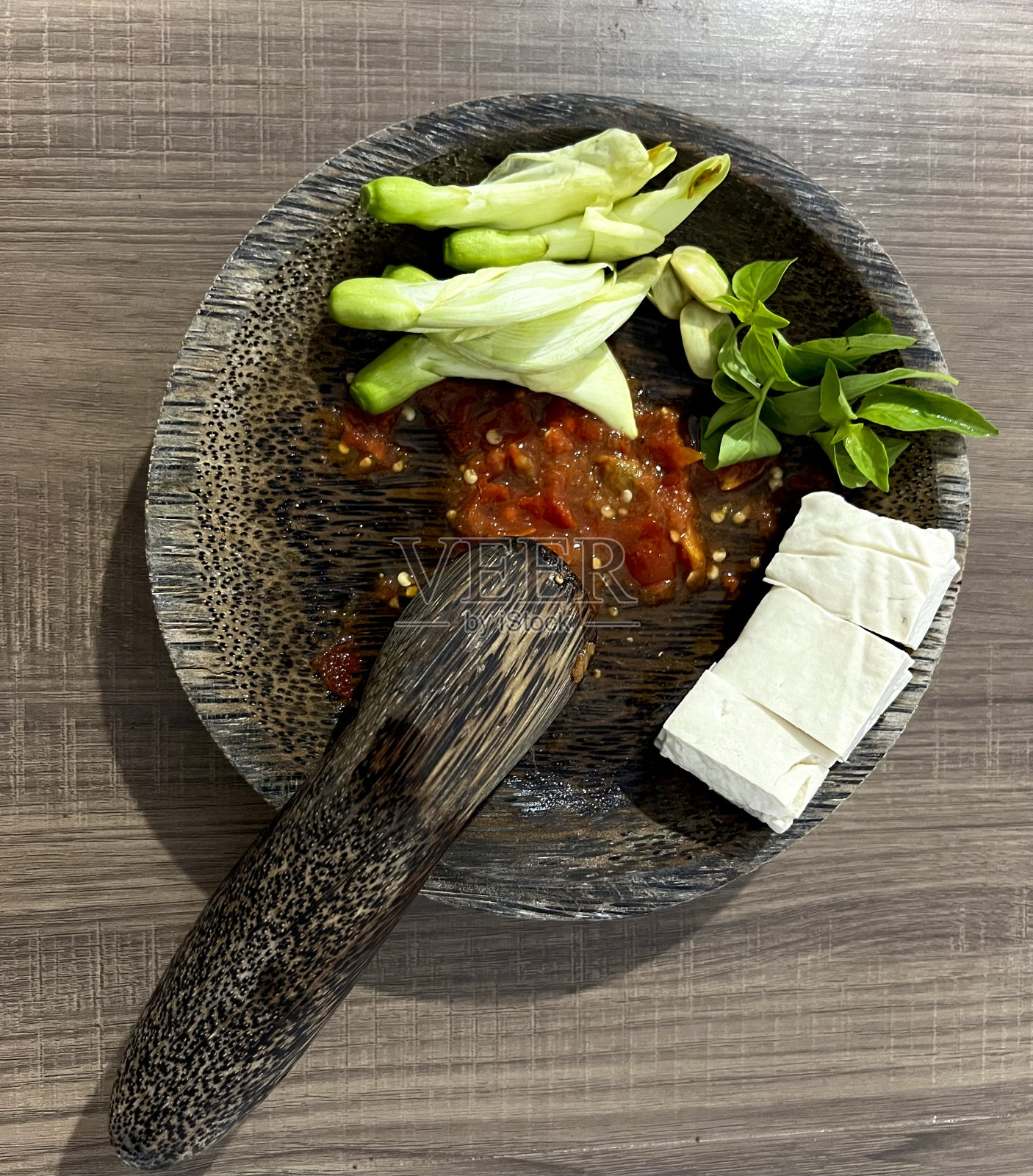 印尼桑巴terasi用的是木臼，里面有生豆腐、大田叶、花瓣和罗勒叶。照片摄影图片