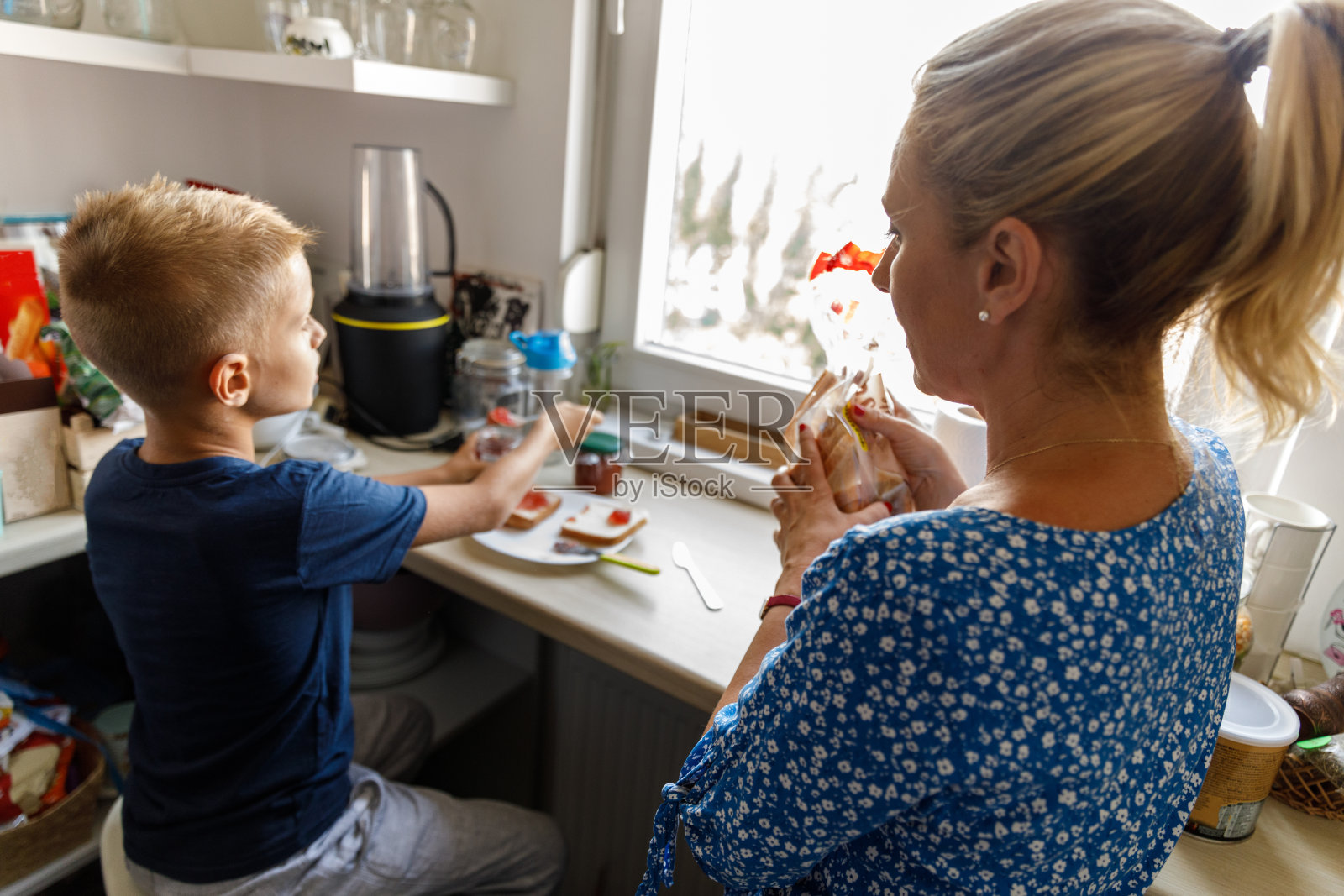 小男孩和他妈妈在厨房做果酱三明治照片摄影图片