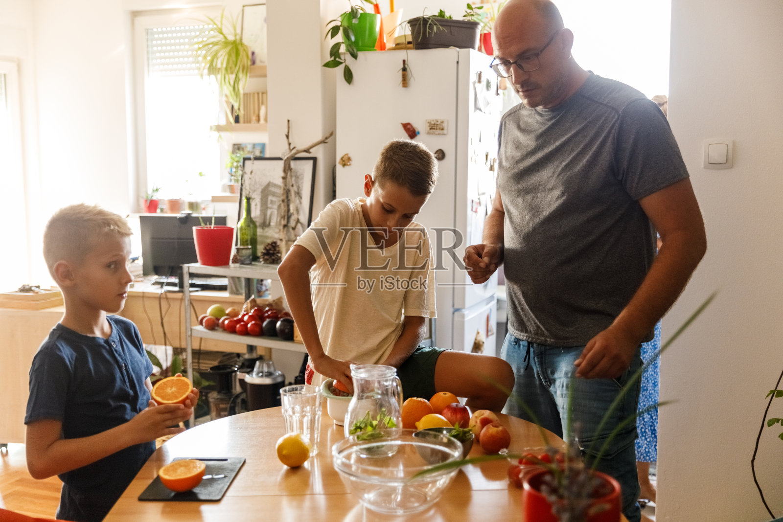 有两个孩子的家庭在餐桌上制作新鲜的柑橘汁照片摄影图片