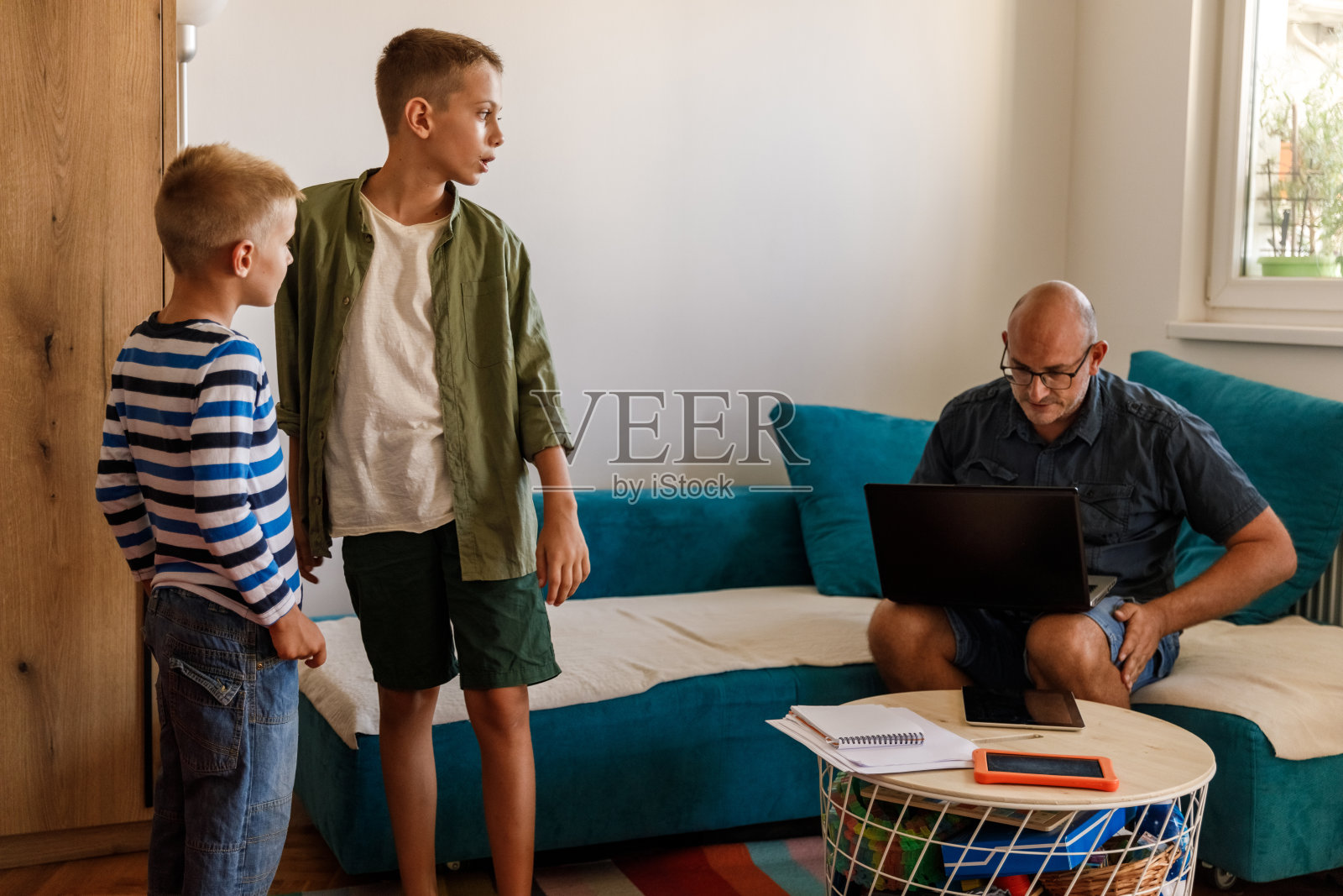 两个男孩在父亲在家工作时分散他的注意力照片摄影图片