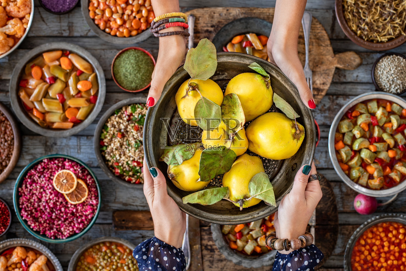两个女人的手捧着铜碗里新鲜而成熟的葡萄。照片摄影图片