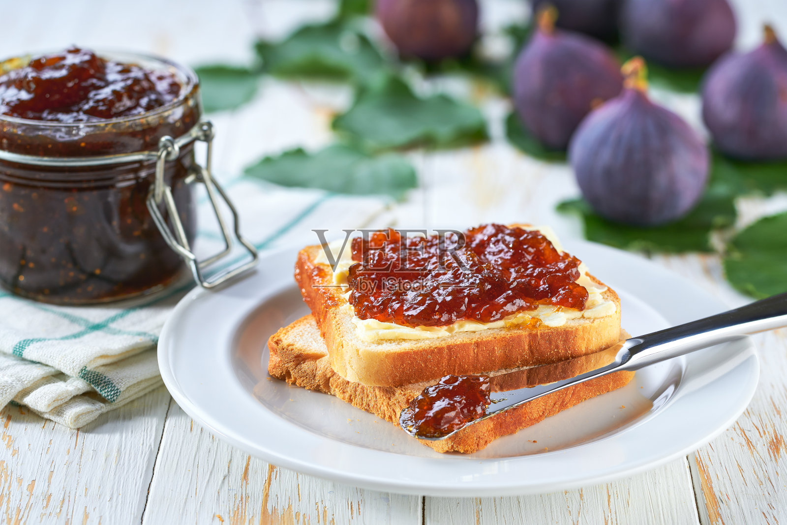 木桌上有面包片和美味的无花果果酱。白色木桌上的烤面包配上美味的无花果果酱。照片摄影图片