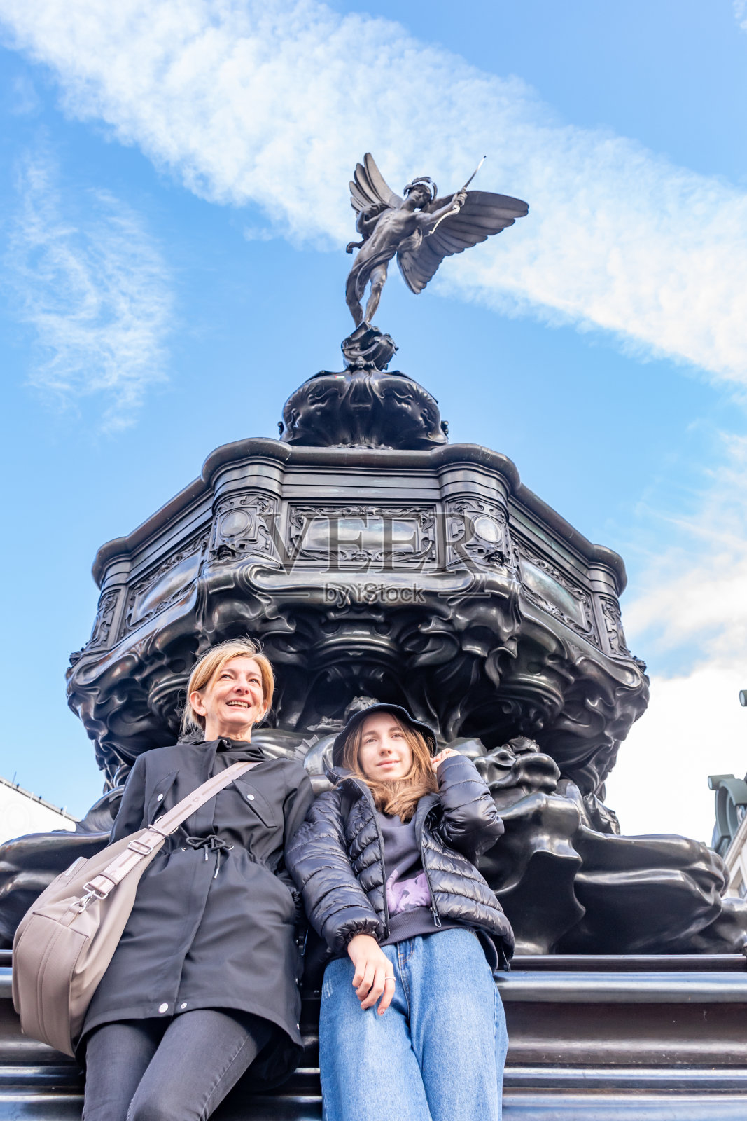 母女俩去伦敦旅行，在英格兰市皮卡迪利广场的爱神雕像前摆姿势照片摄影图片
