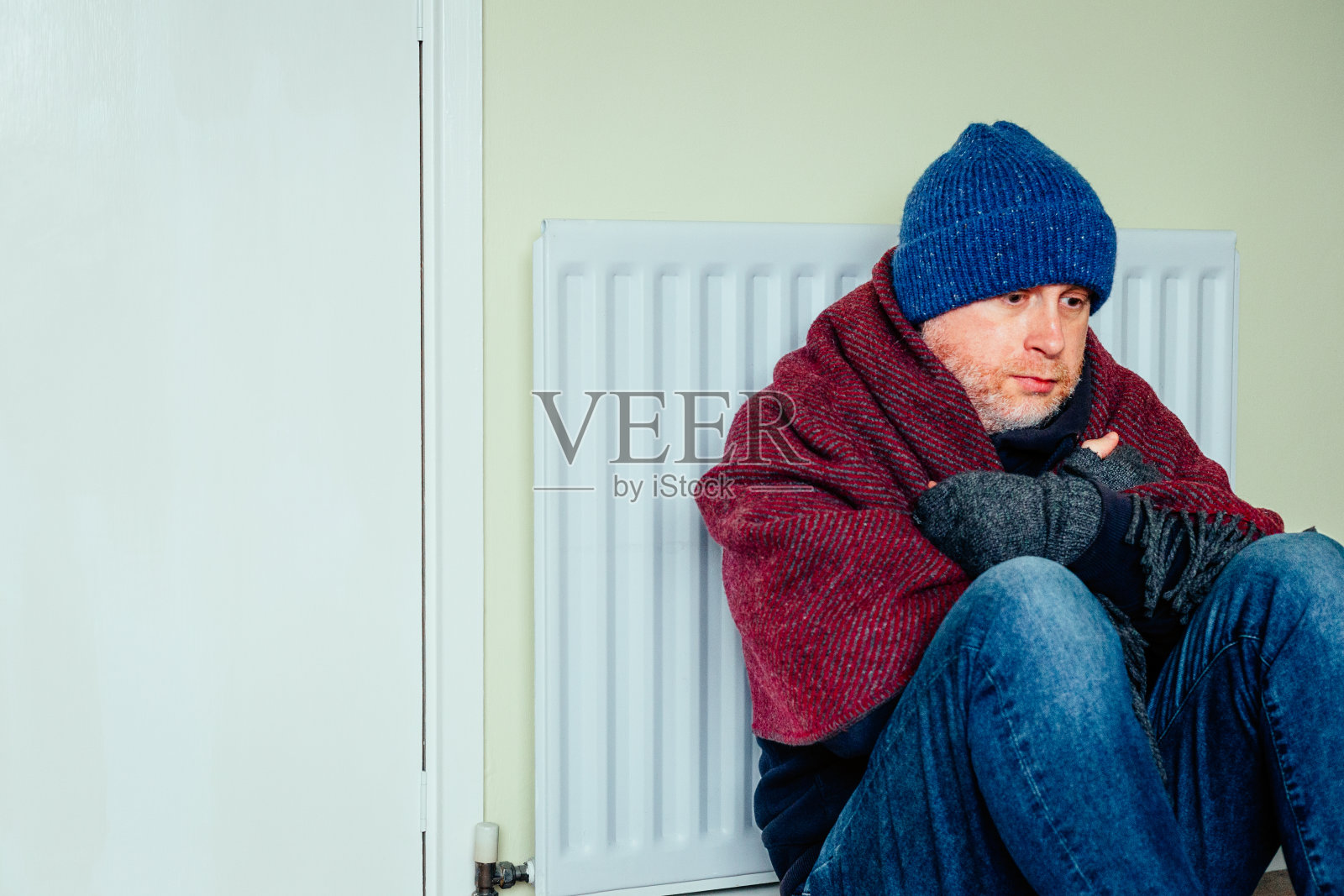 中年男子在冬天坐在暖气片旁边照片摄影图片